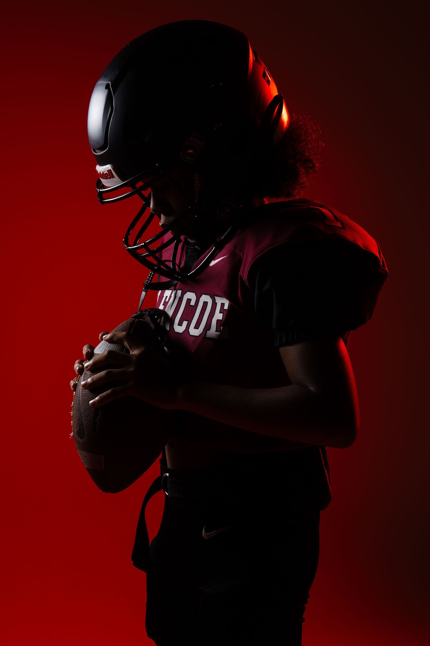 Moody red-lit portrait of football player in protective gear.