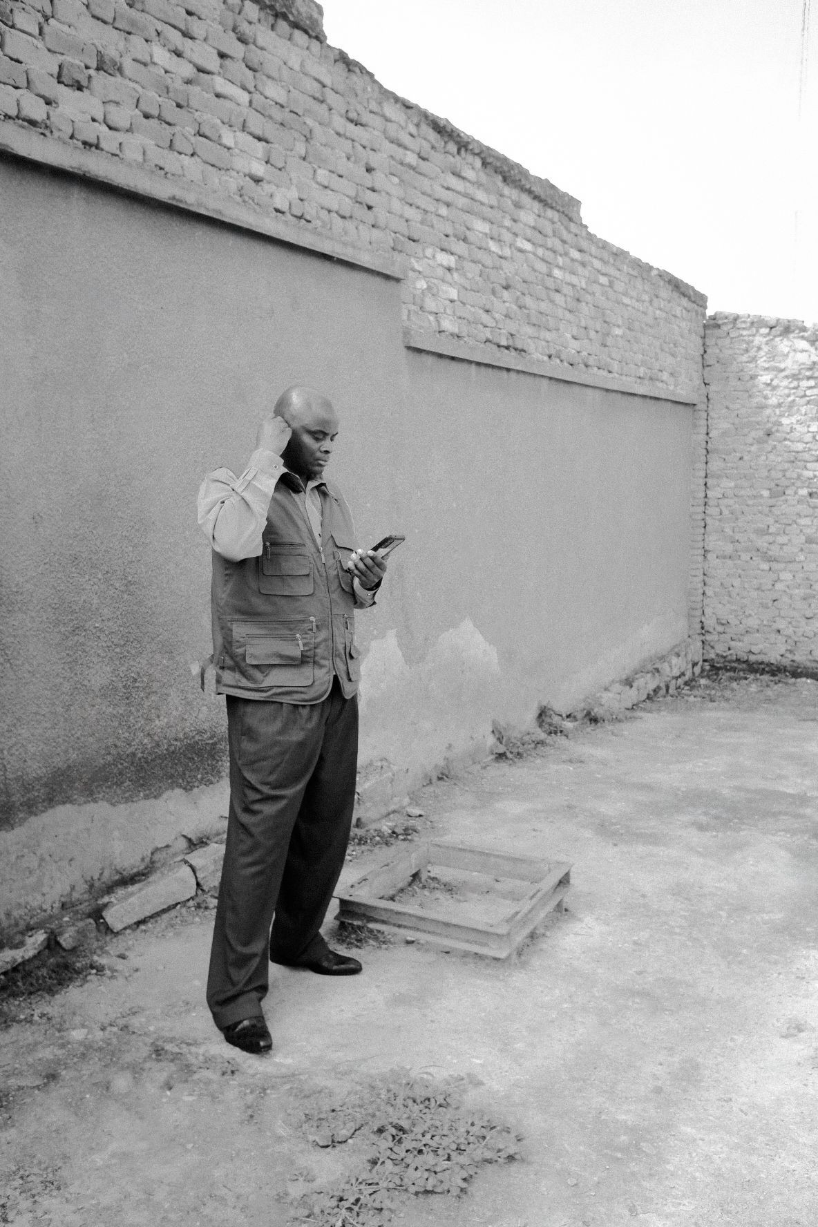 Black and white photo of someone walking along a long concrete wall.