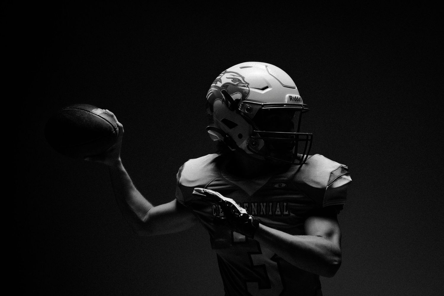 Silhouetted football helmets and equipment in dramatic black and white lighting.