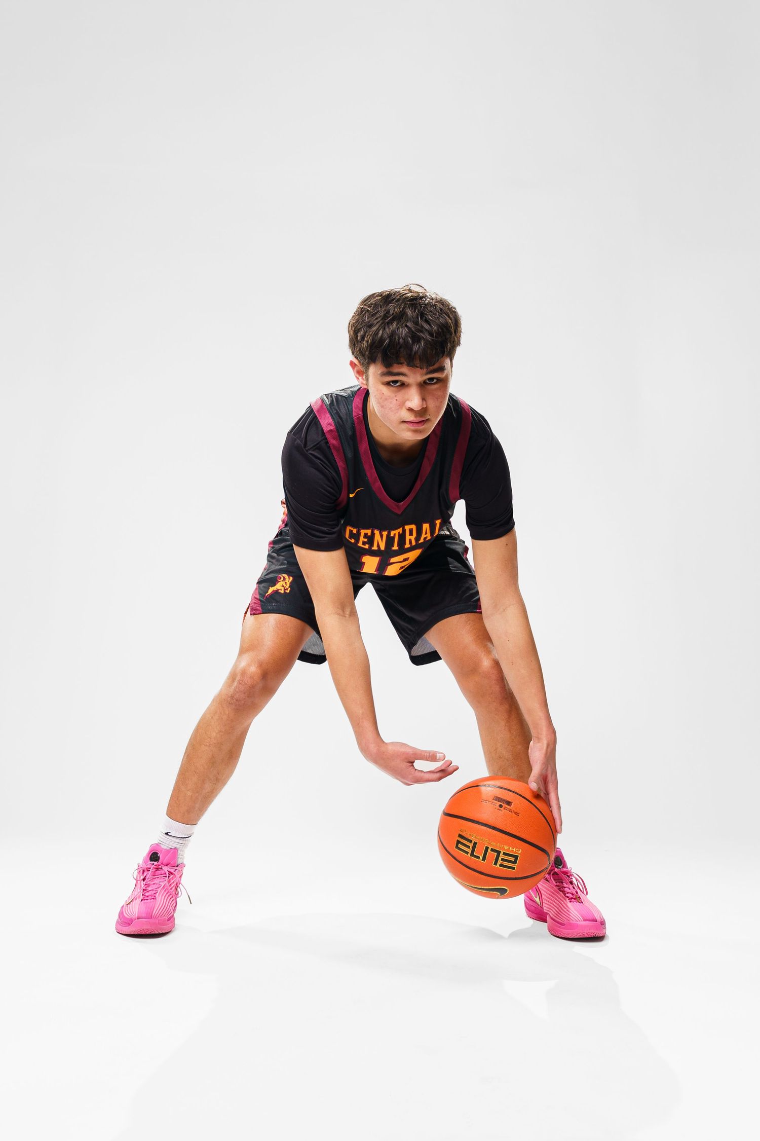 Player in Central Catholic uniform demonstrates low dribbling stance with basketball.