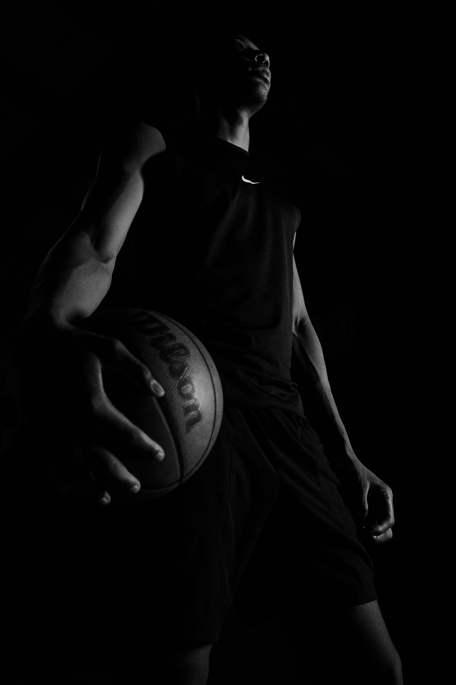 Low key basketball player silhouette holding ball while wearing Nike gear.