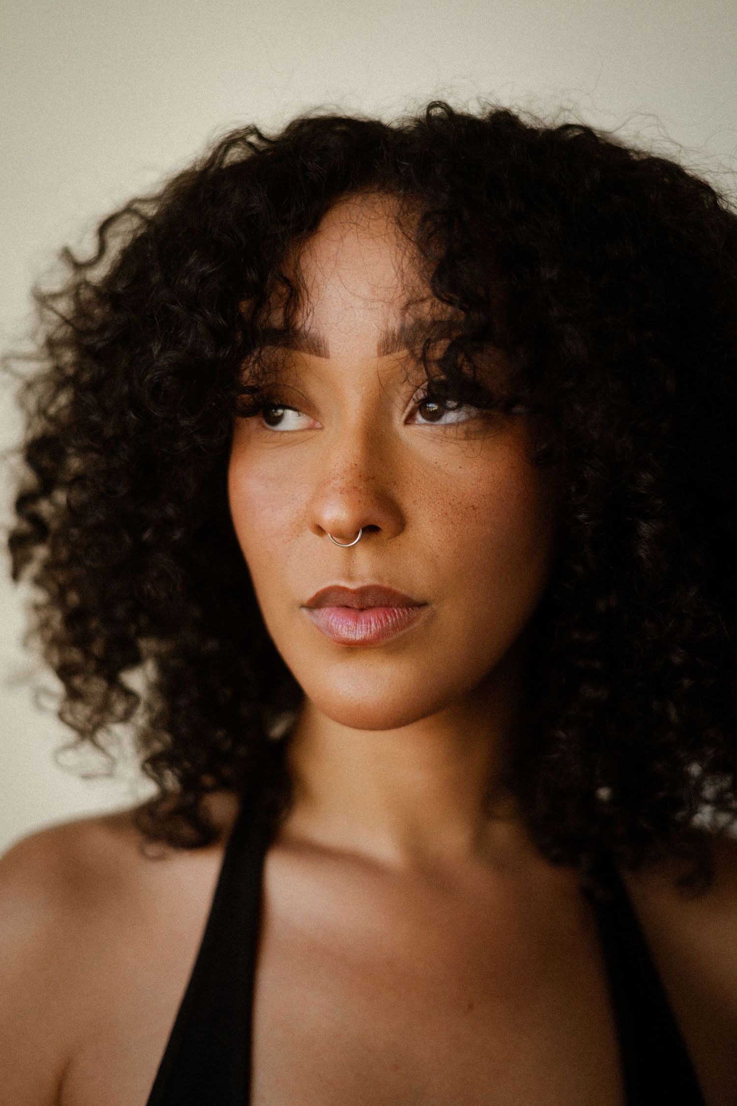Close-up beauty portrait with soft lighting and natural curly hair.