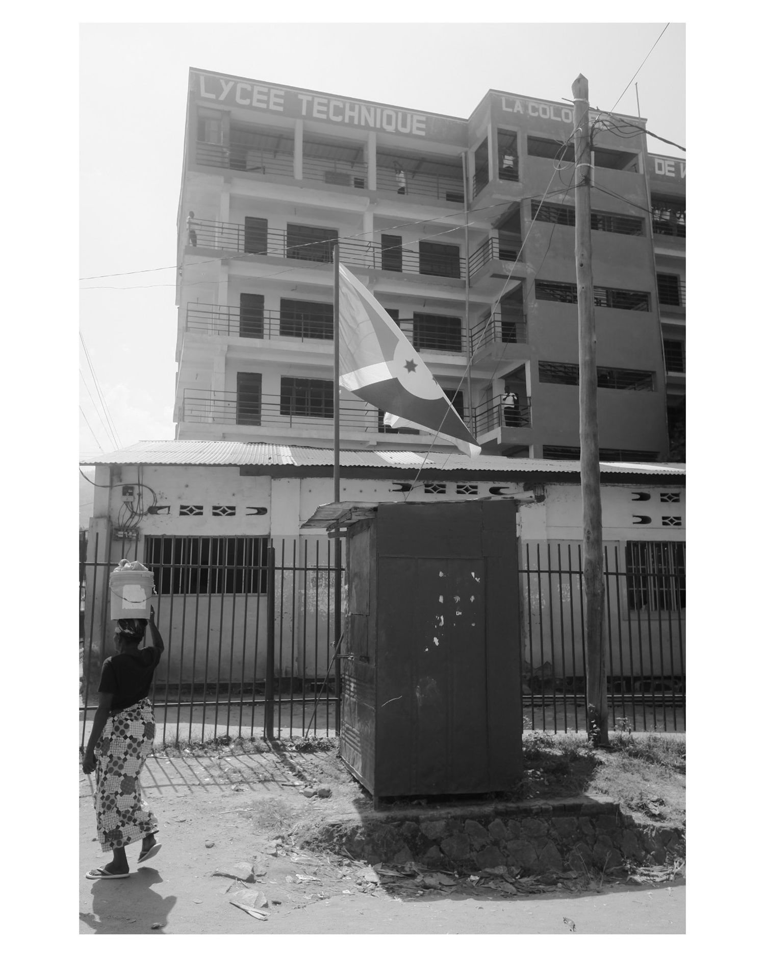 Exterior view of a technical school building with metal fence and flag pole.