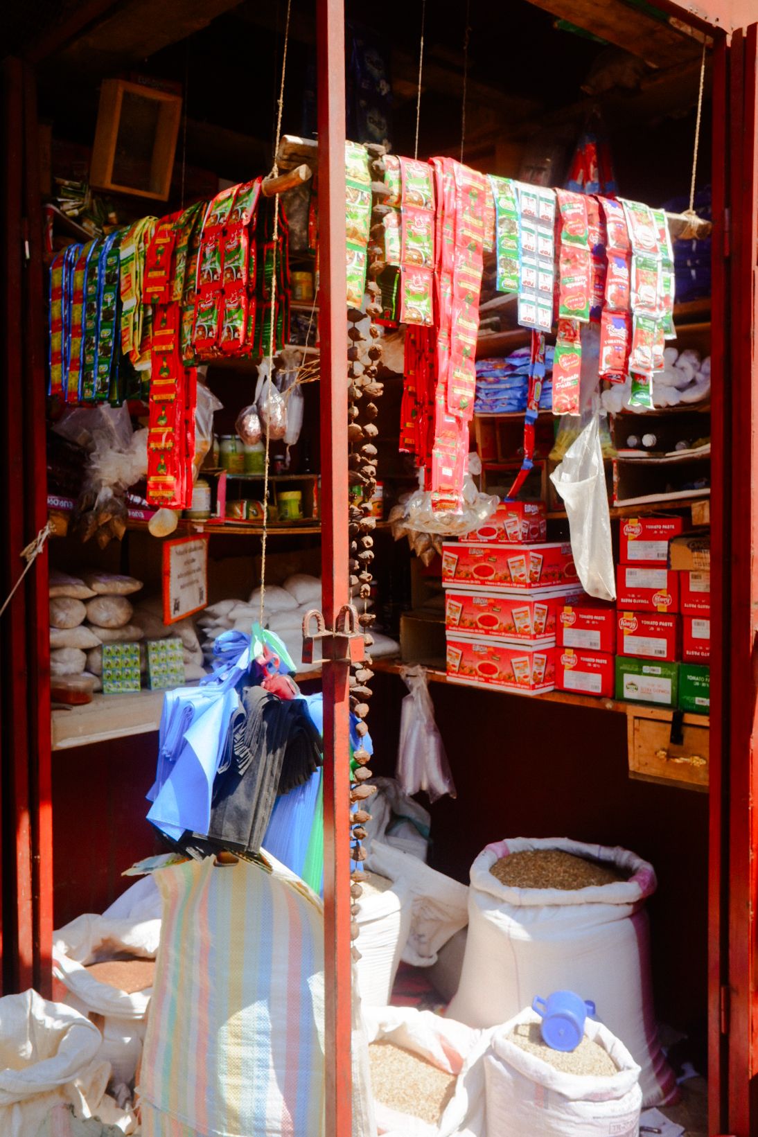 Shop shelves stocked with colorful packaged goods and white sacks on the floor.