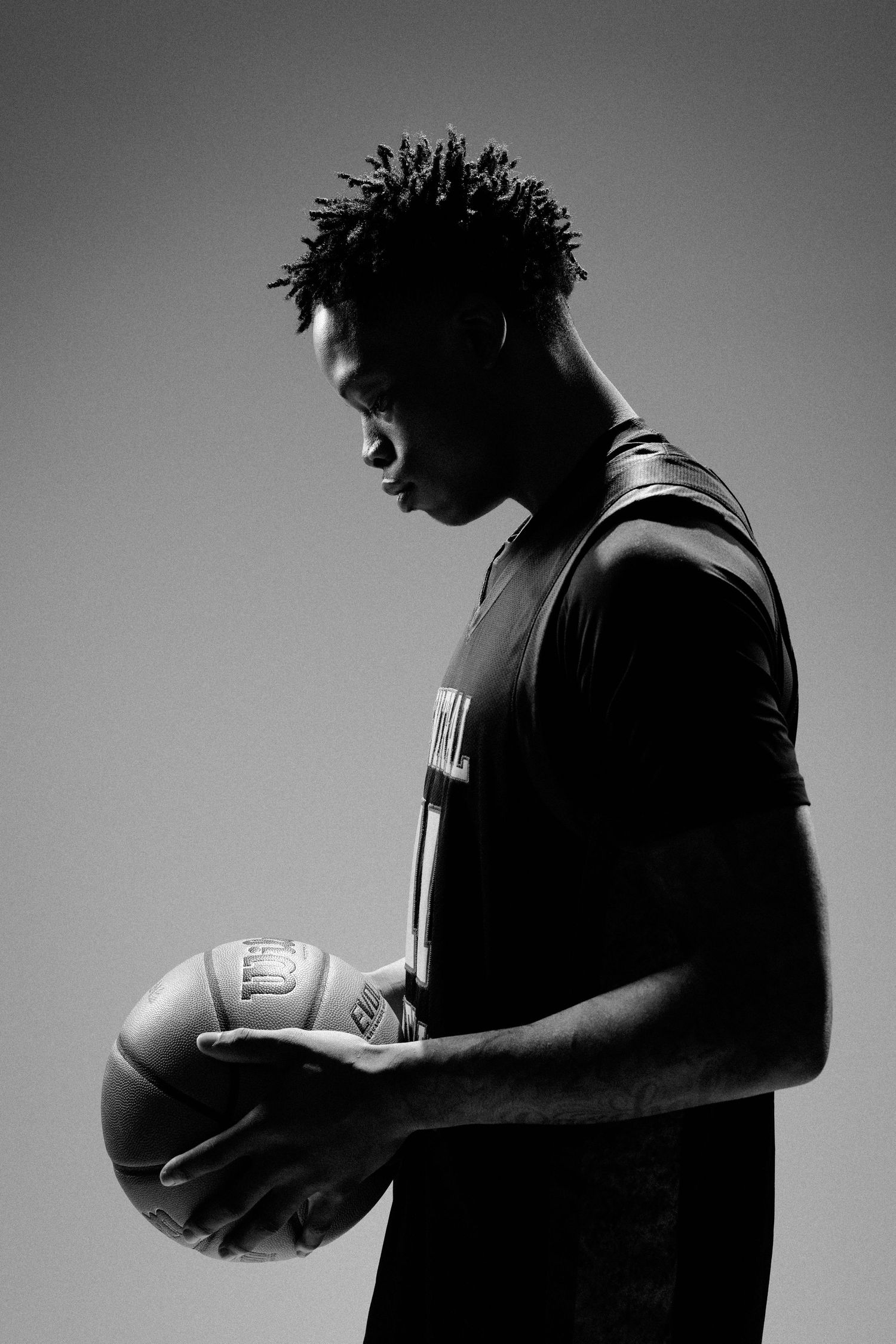 Silhouetted basketball player holding ball in dramatic black and white lighting.