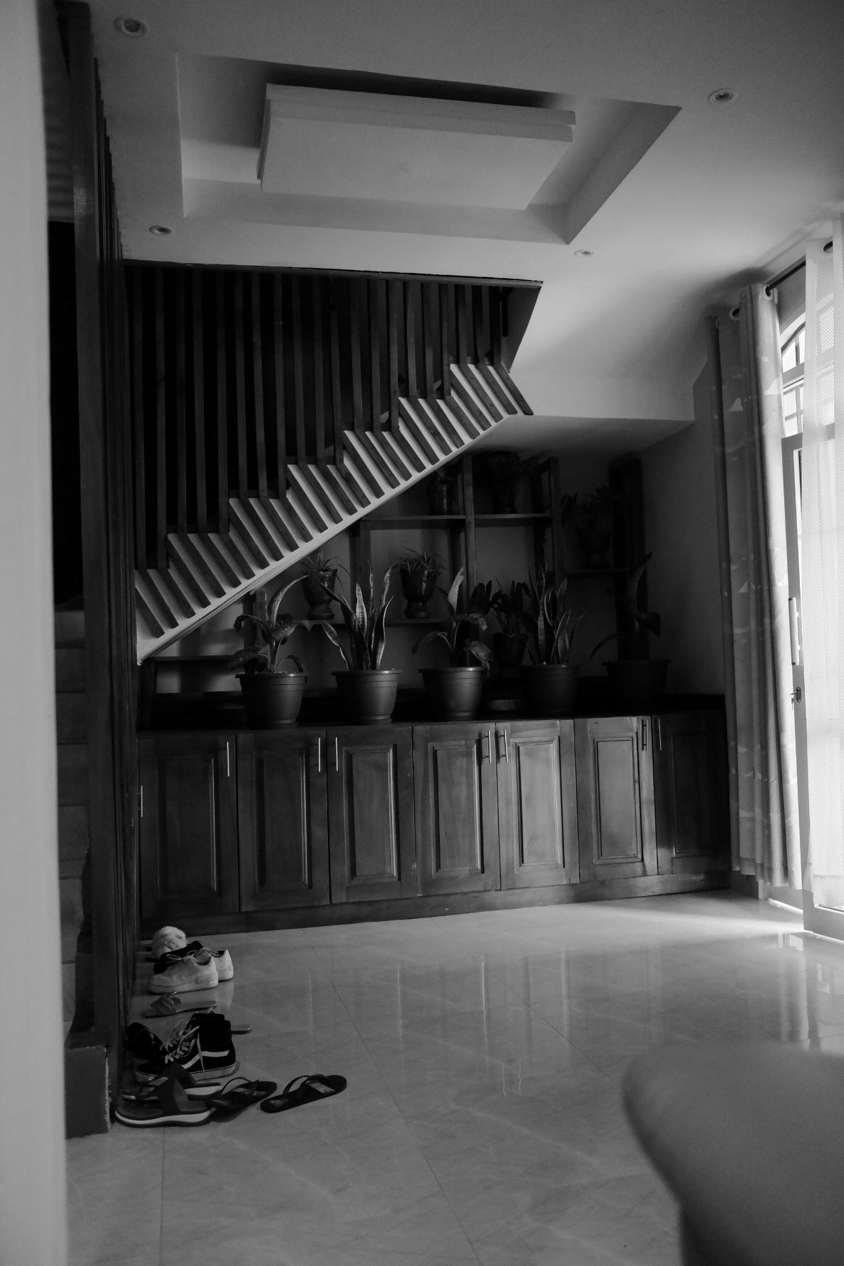 Large empty room with wooden paneling and angled ceiling features in black and white.
