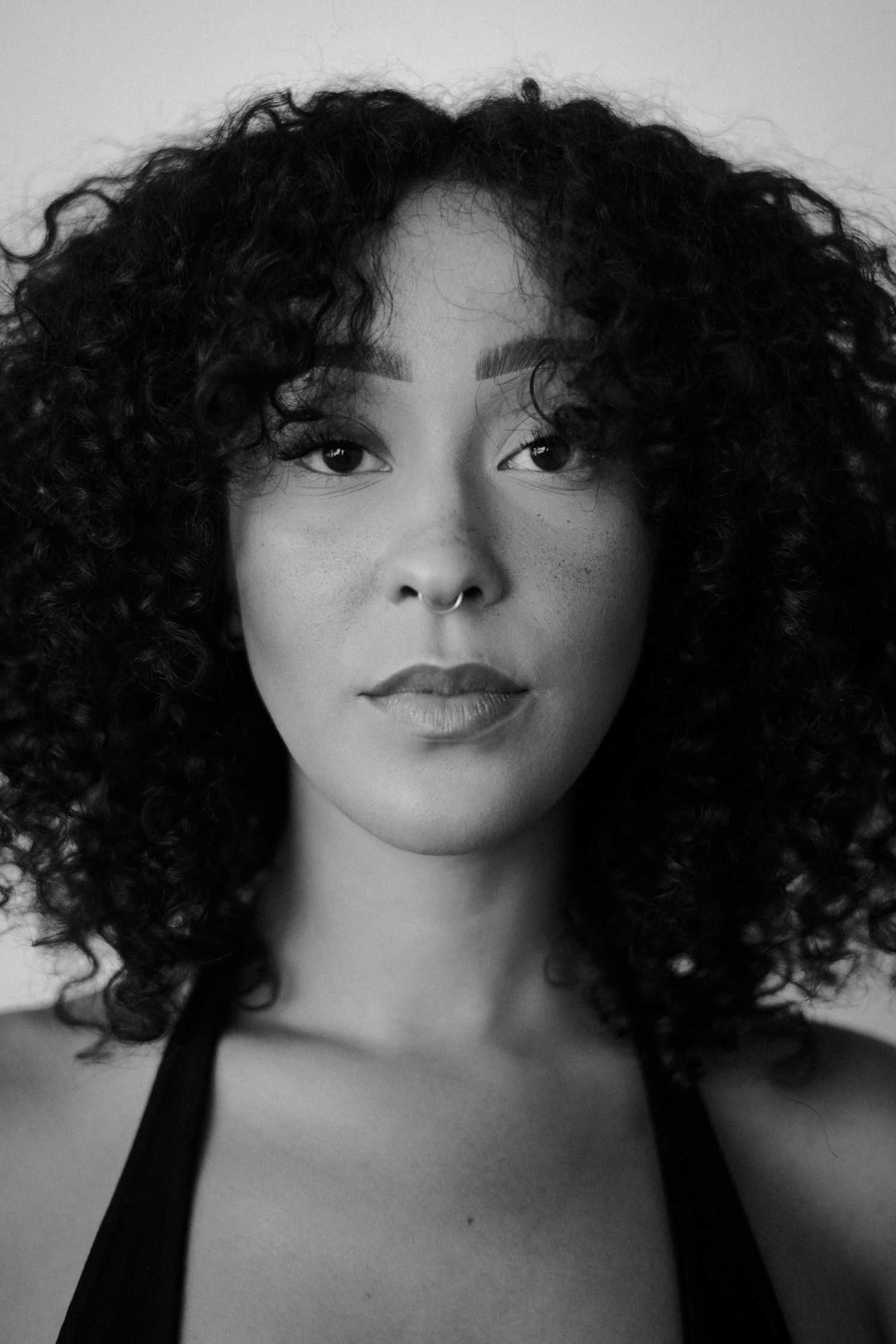 Portrait of woman with natural curly hair against white background.