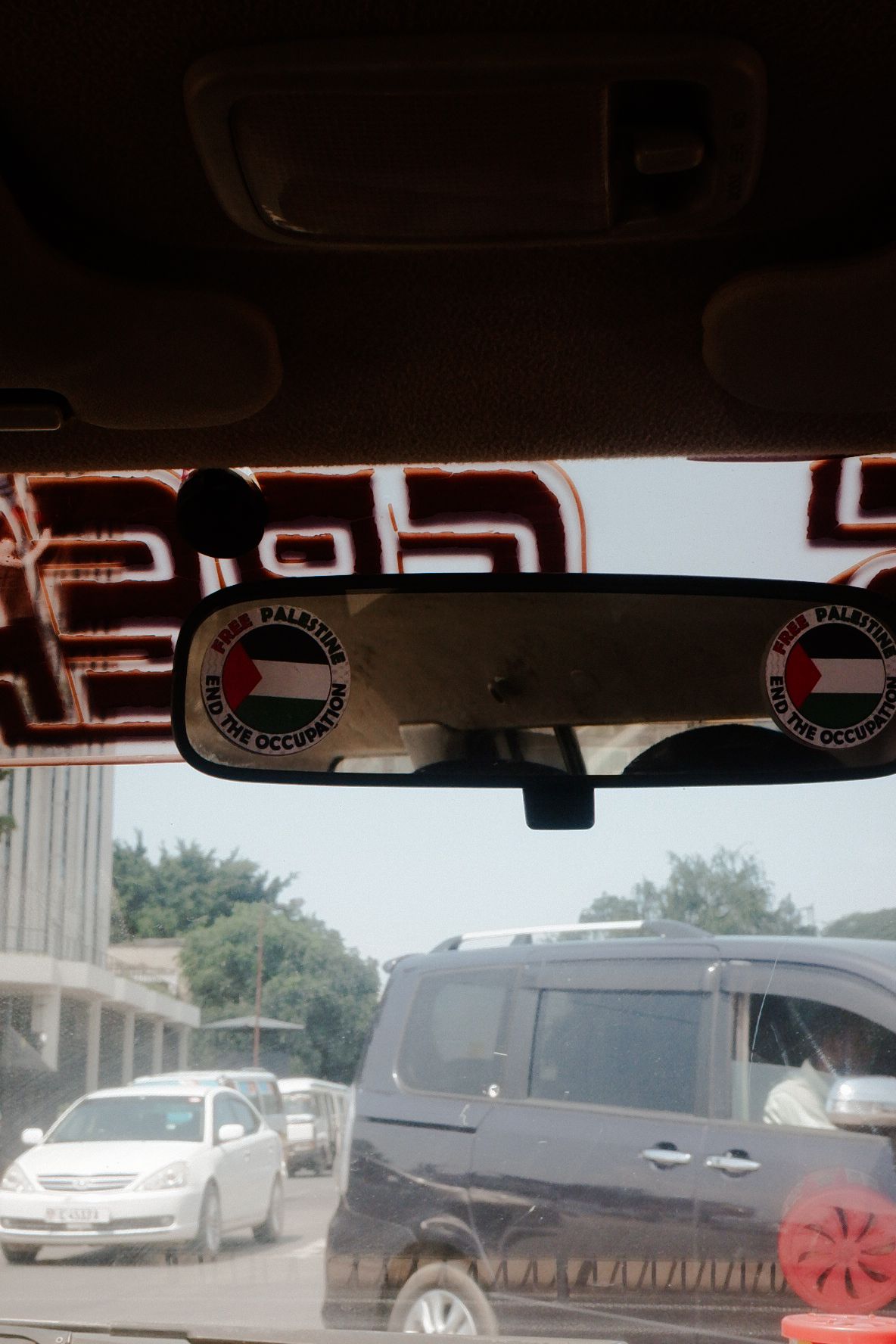 View through a car windshield showing other vehicles on a sunny road.
