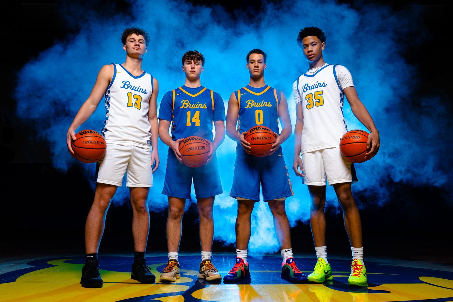 Basketball team poses in blue and white uniforms with dramatic smoke effects.
