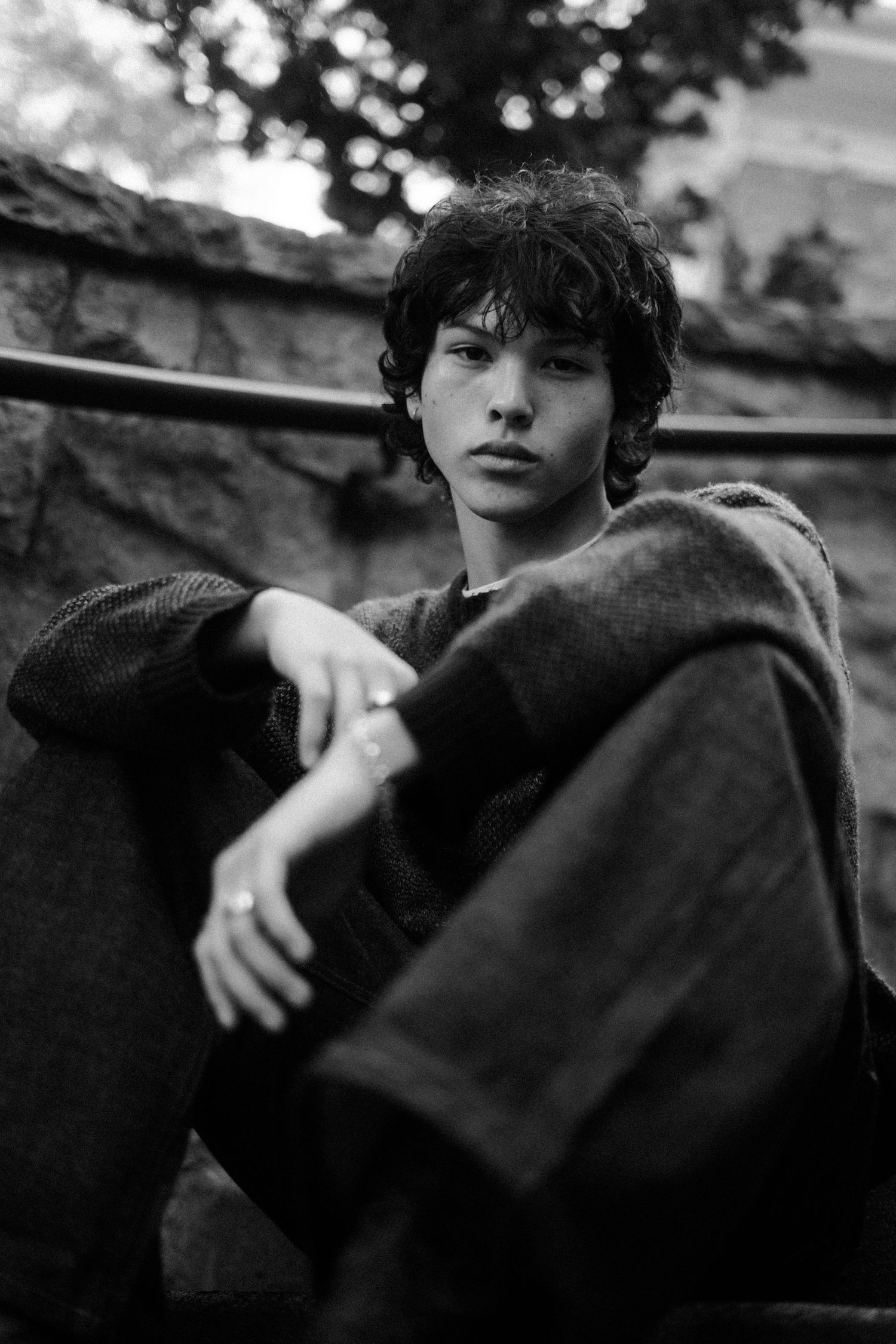 Artistic black and white photo of person resting on stone bench.