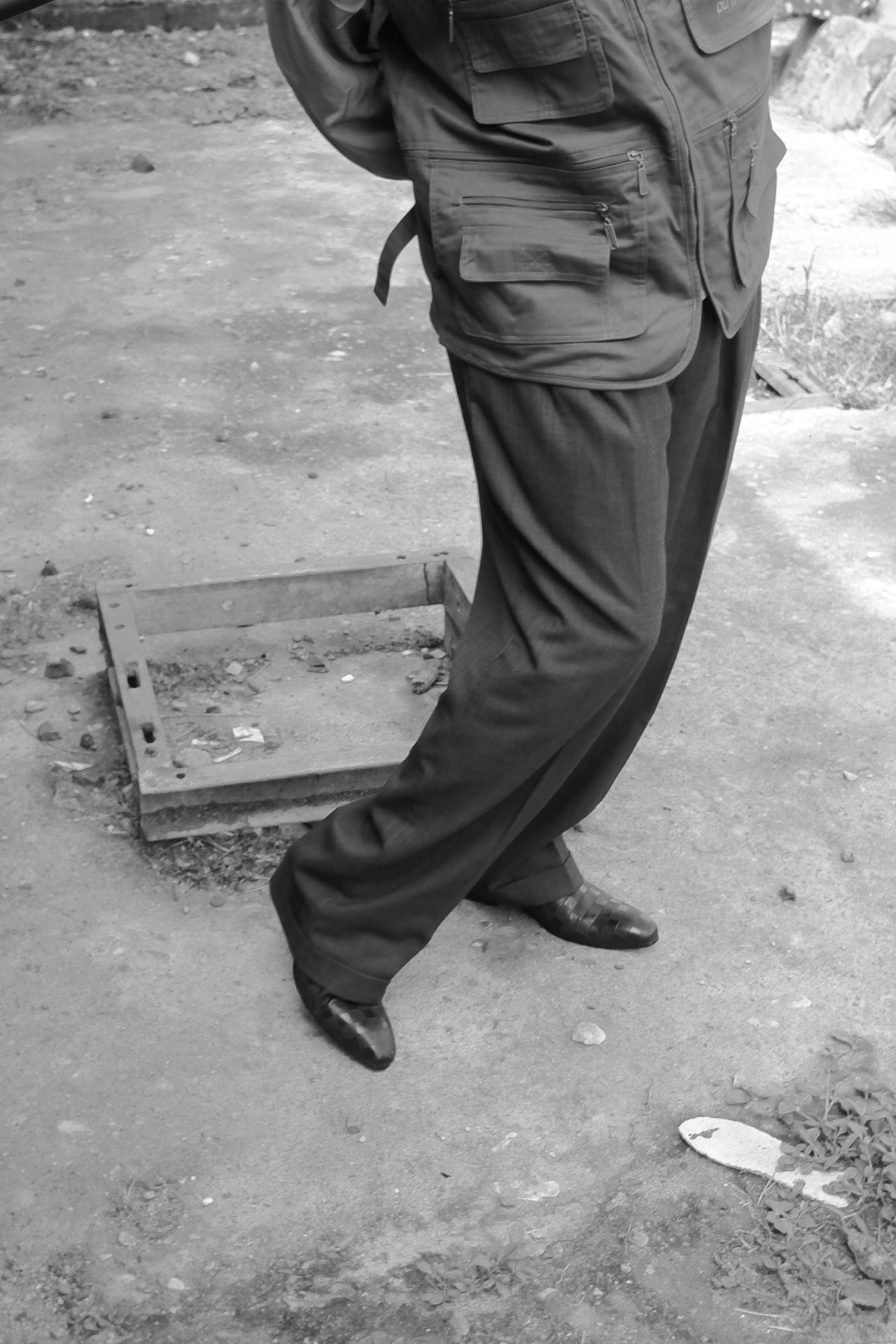 Close-up view of legs and feet in casual pants on concrete ground.
