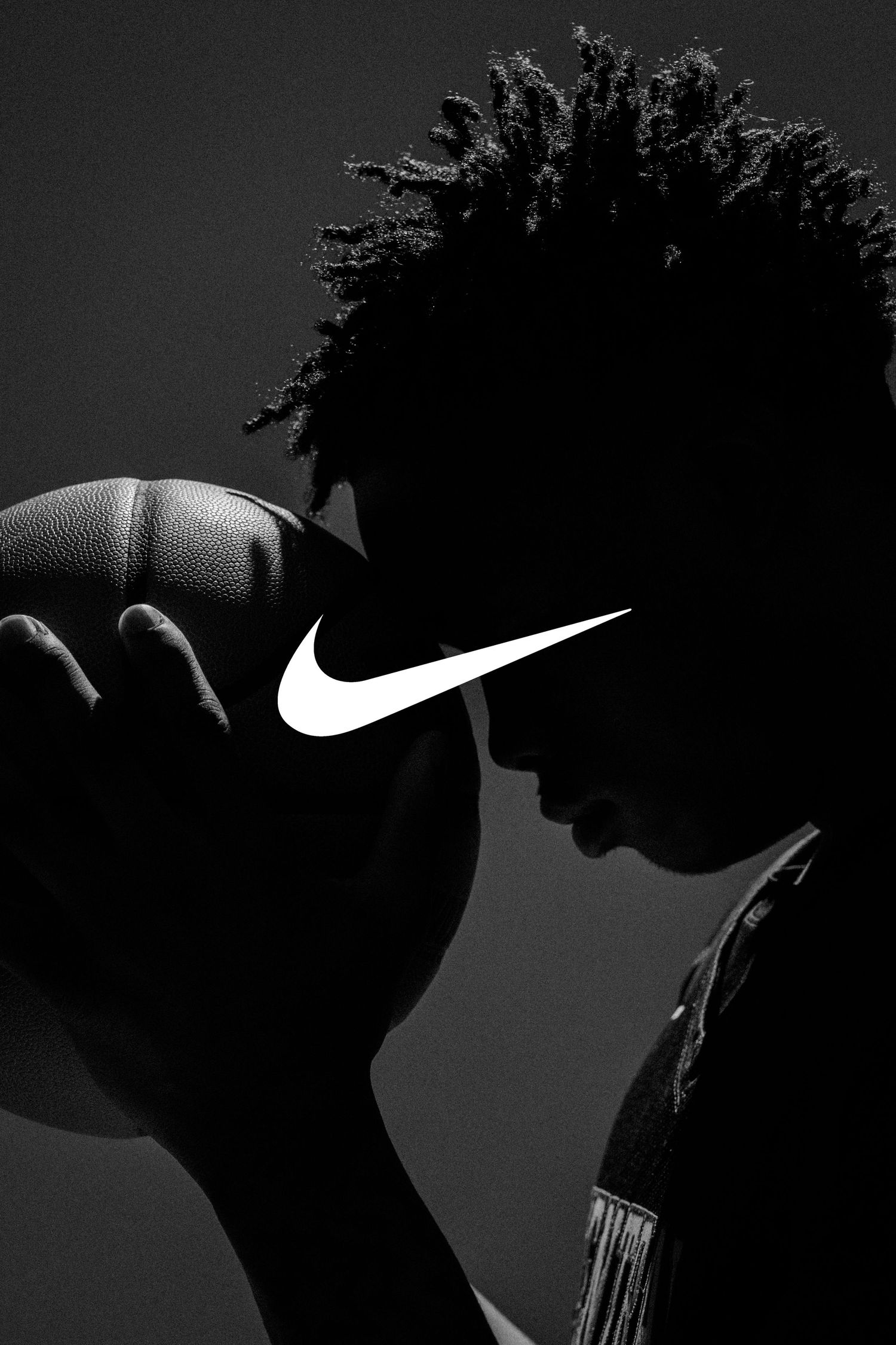 A dramatic black and white silhouette of an athlete wearing a Nike cap against a dark background.