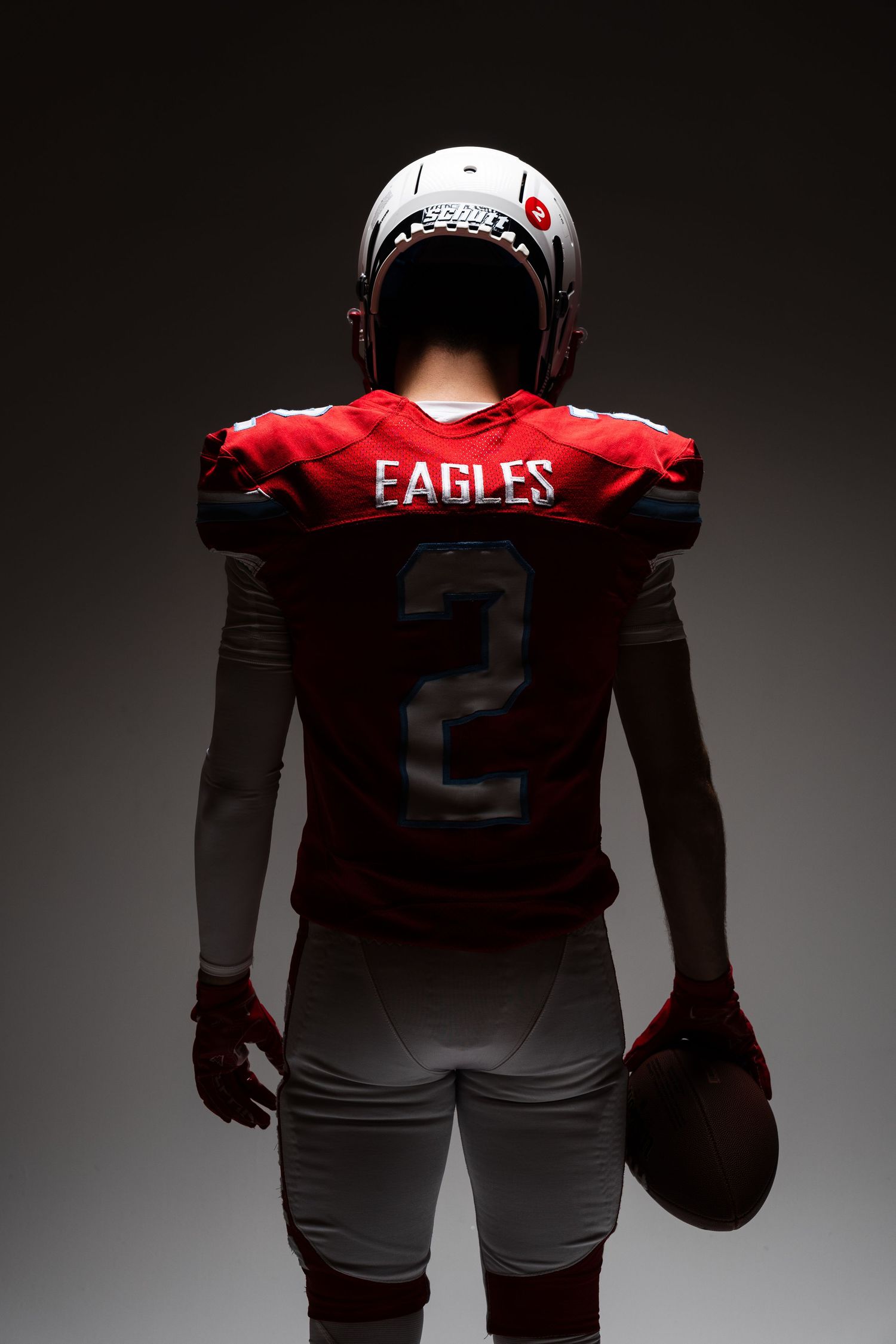 Dramatic silhouette of football player wearing Eagles jersey in moody studio lighting.