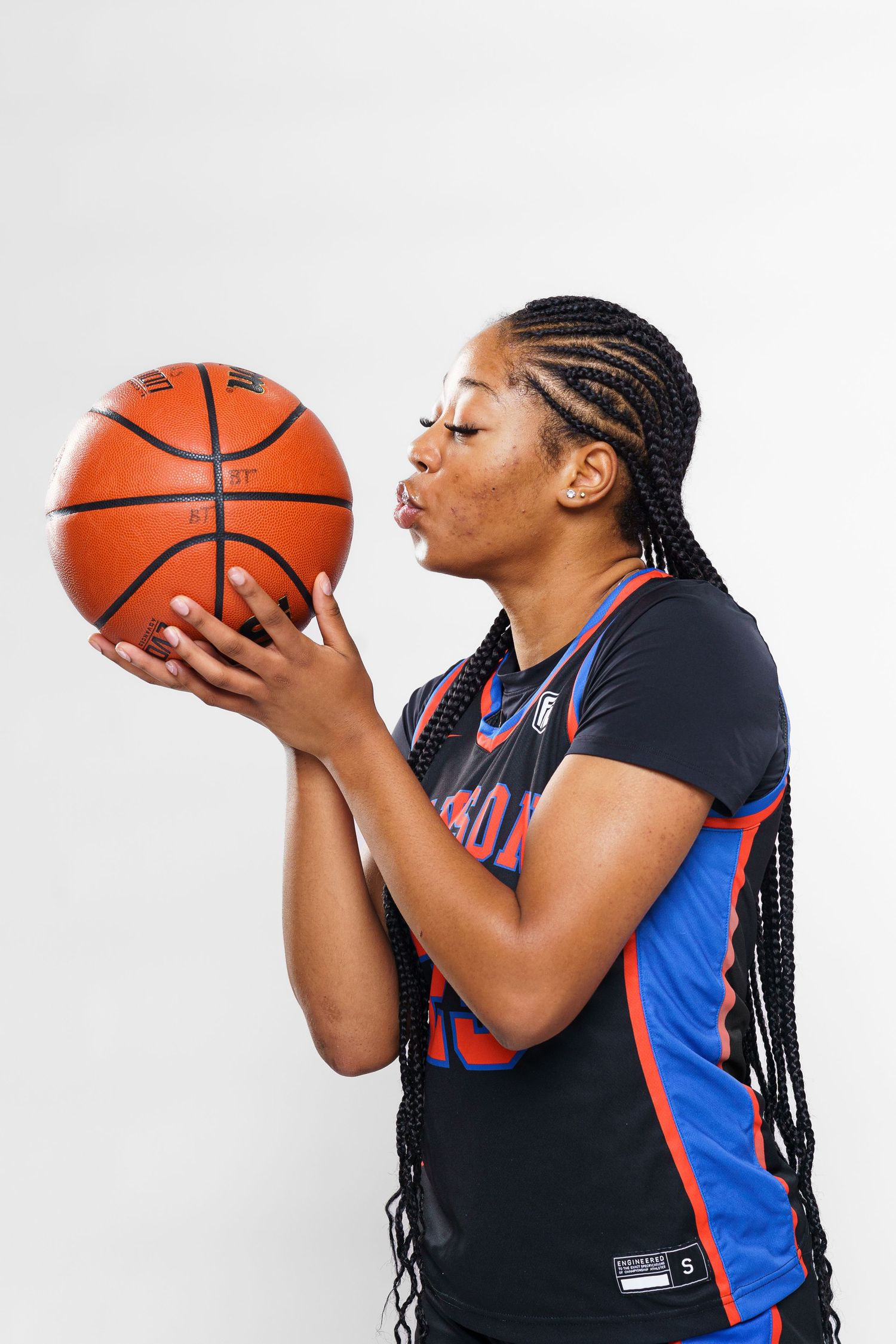 Basketball player in navy and blue uniform posing with ball in studio sequence.