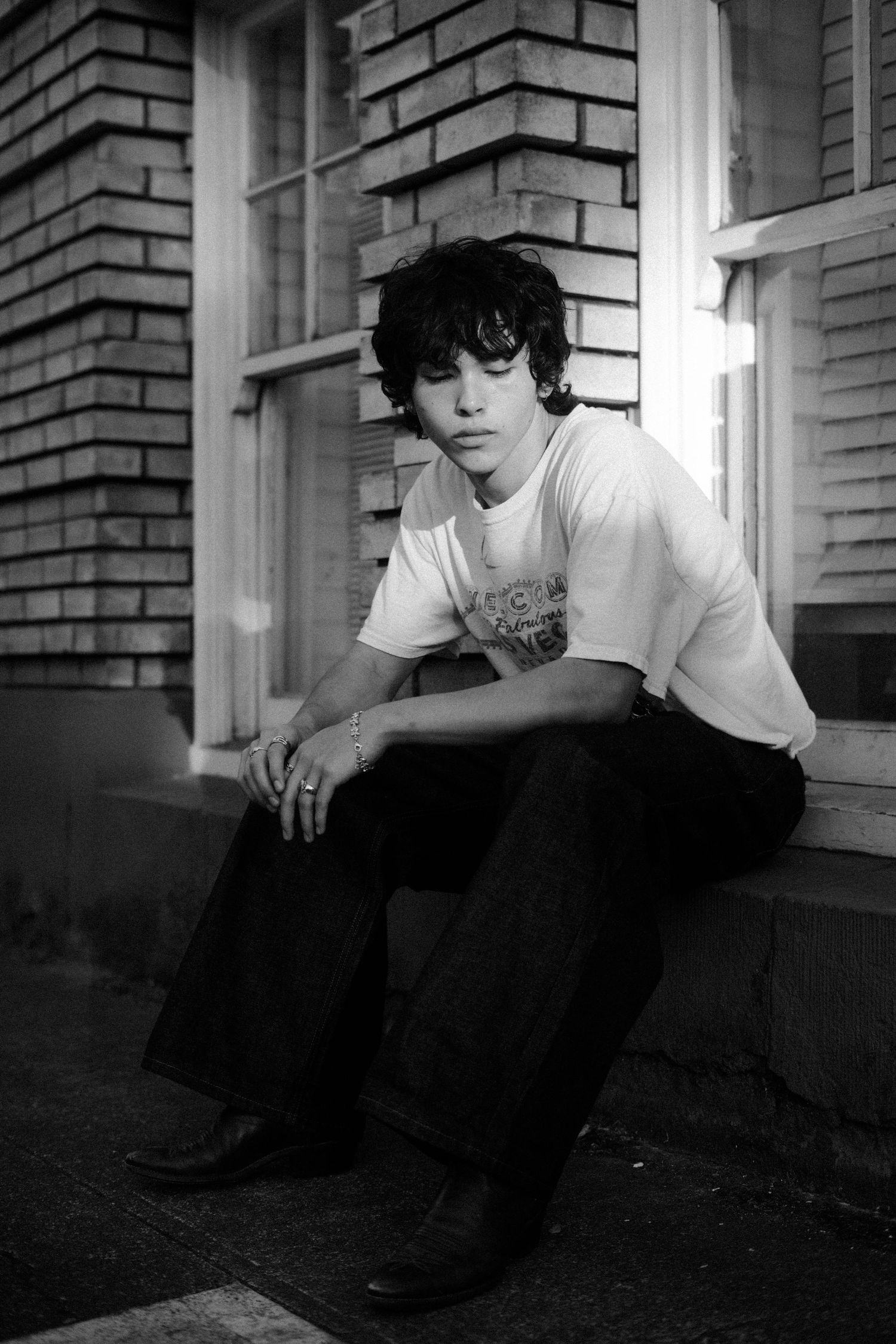 Pensive poses on brick building ledge in monochromatic tones.
