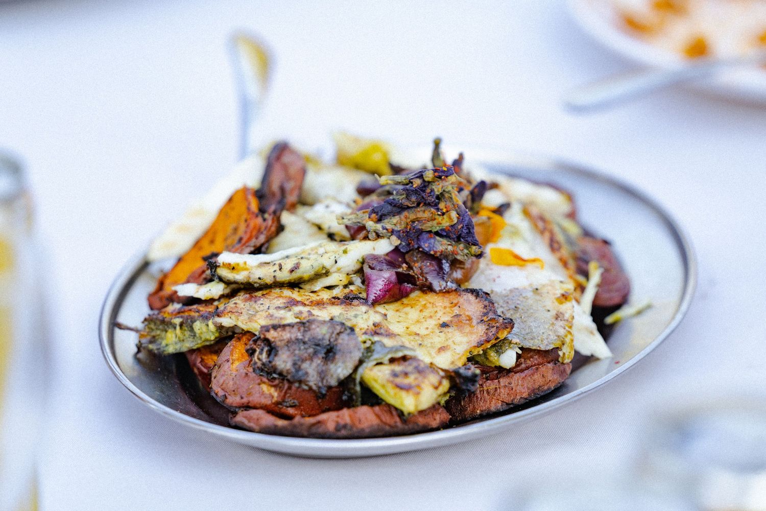 A plate of grilled mixed vegetables and meat with roasted squash, cabbage, and caramelized onions served on a white dish.