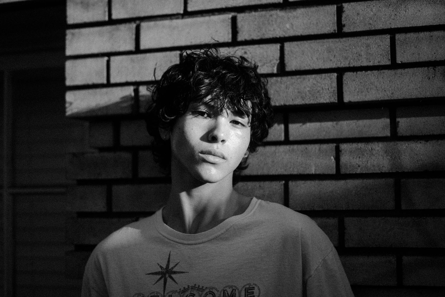 Moody black and white portrait sequence against brick wall background.