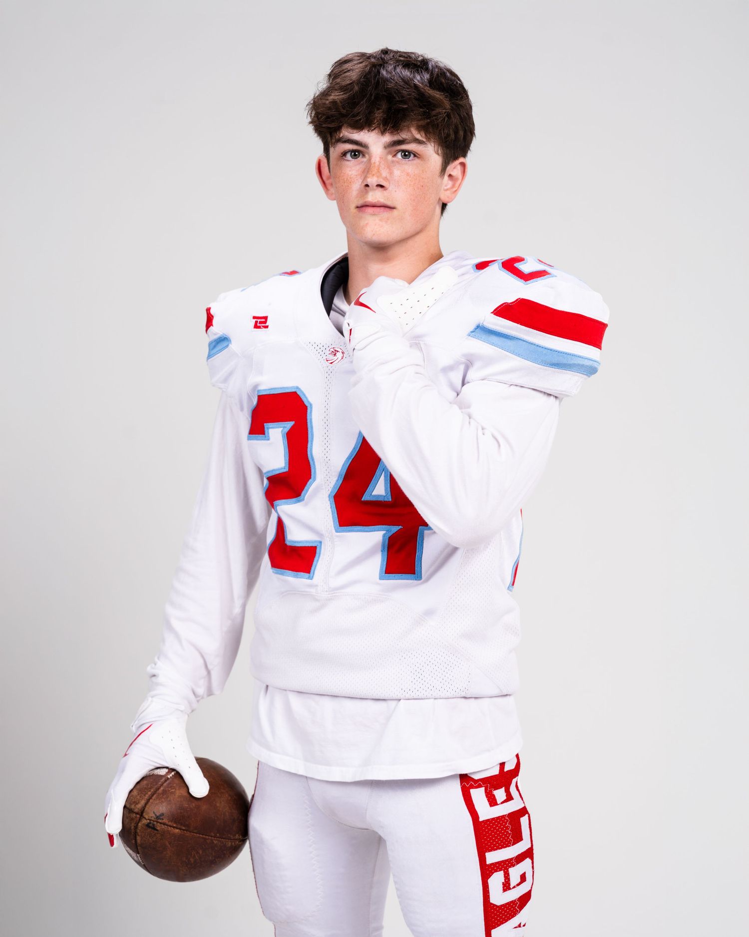 Sports themed photo shoot with white uniform and red numbering against light background.