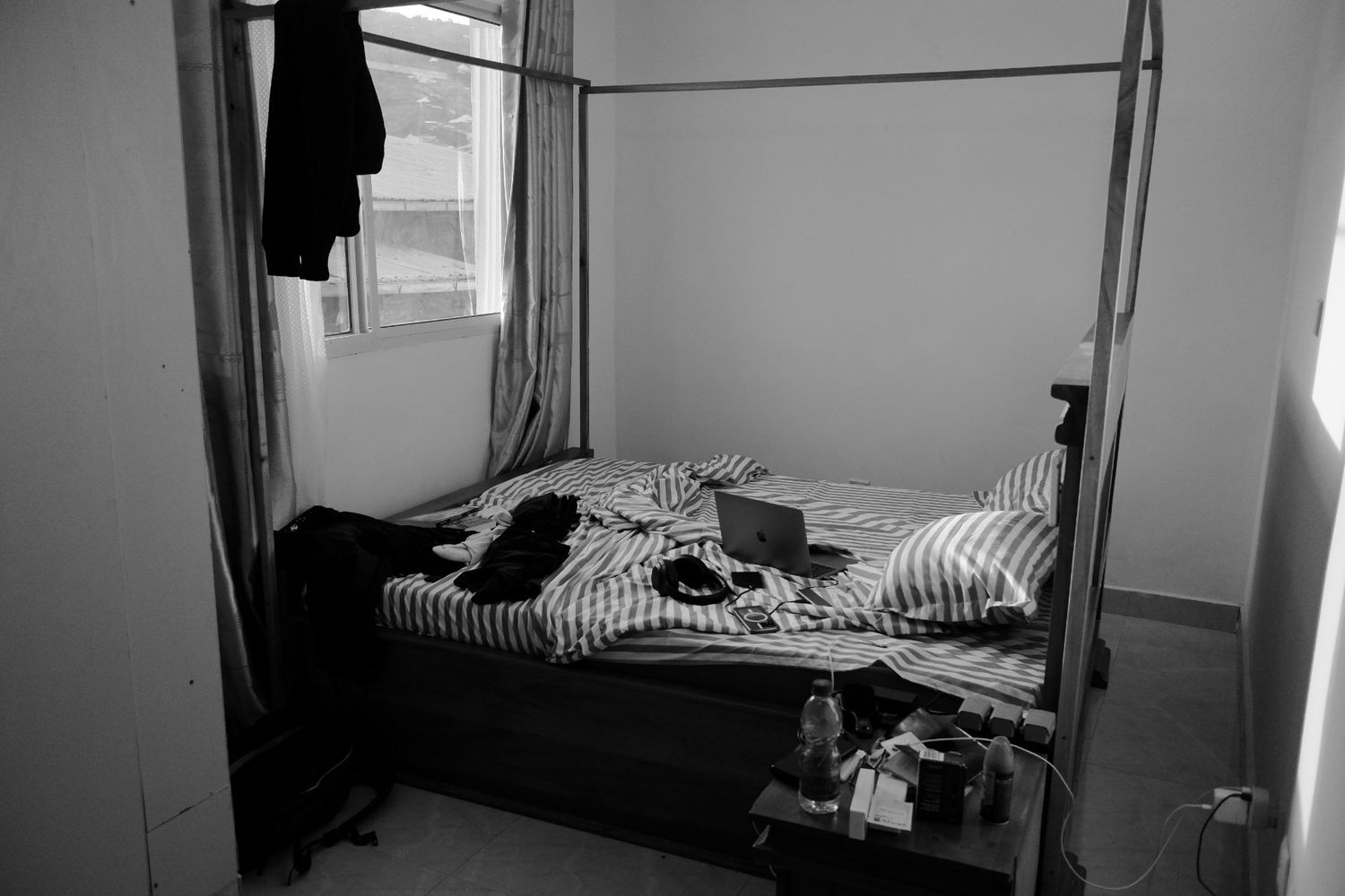 Empty dormitory room with multiple beds arranged in a row against white walls.