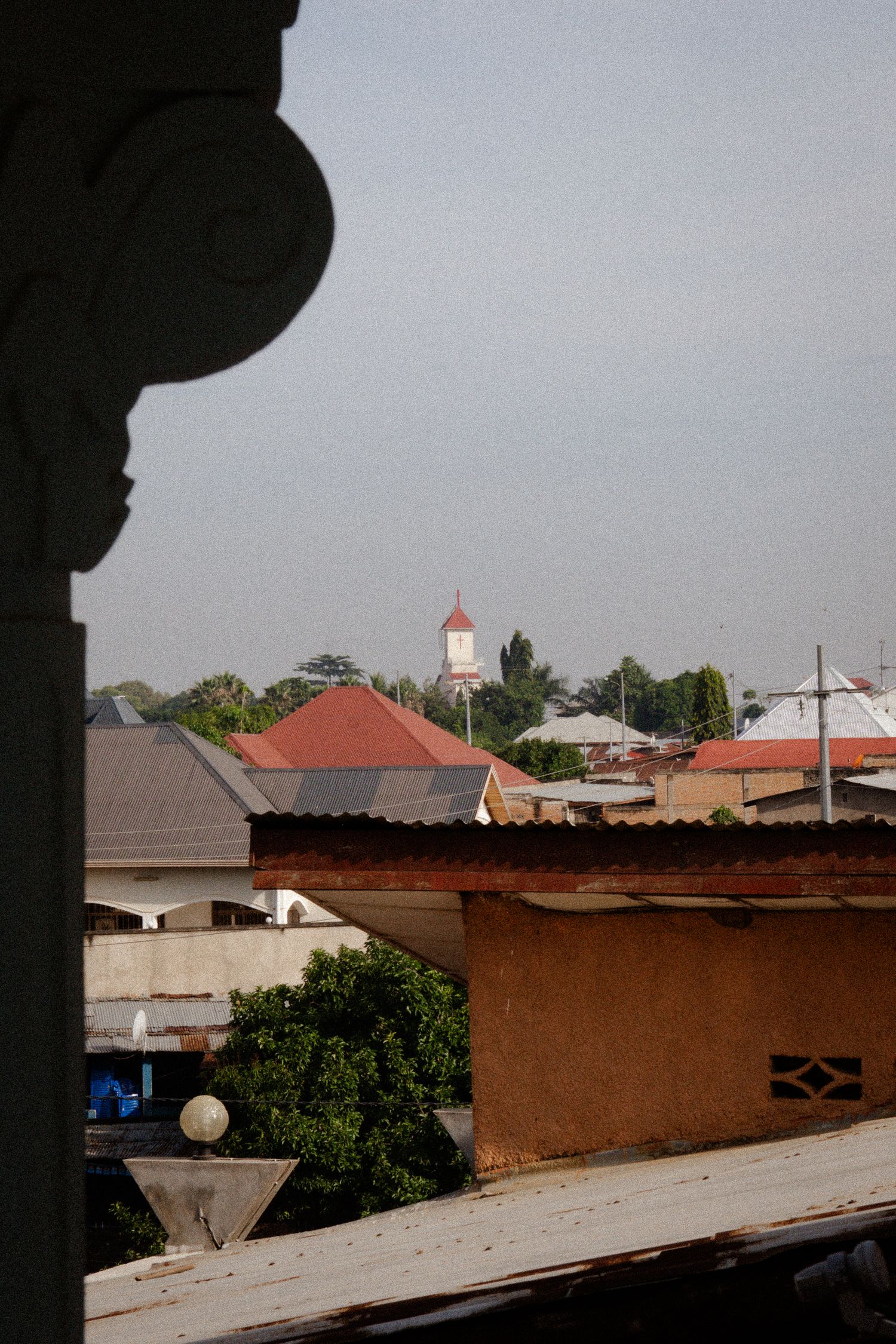 Aerial view of residential buildings with red roofs and a church steeple in the distance.