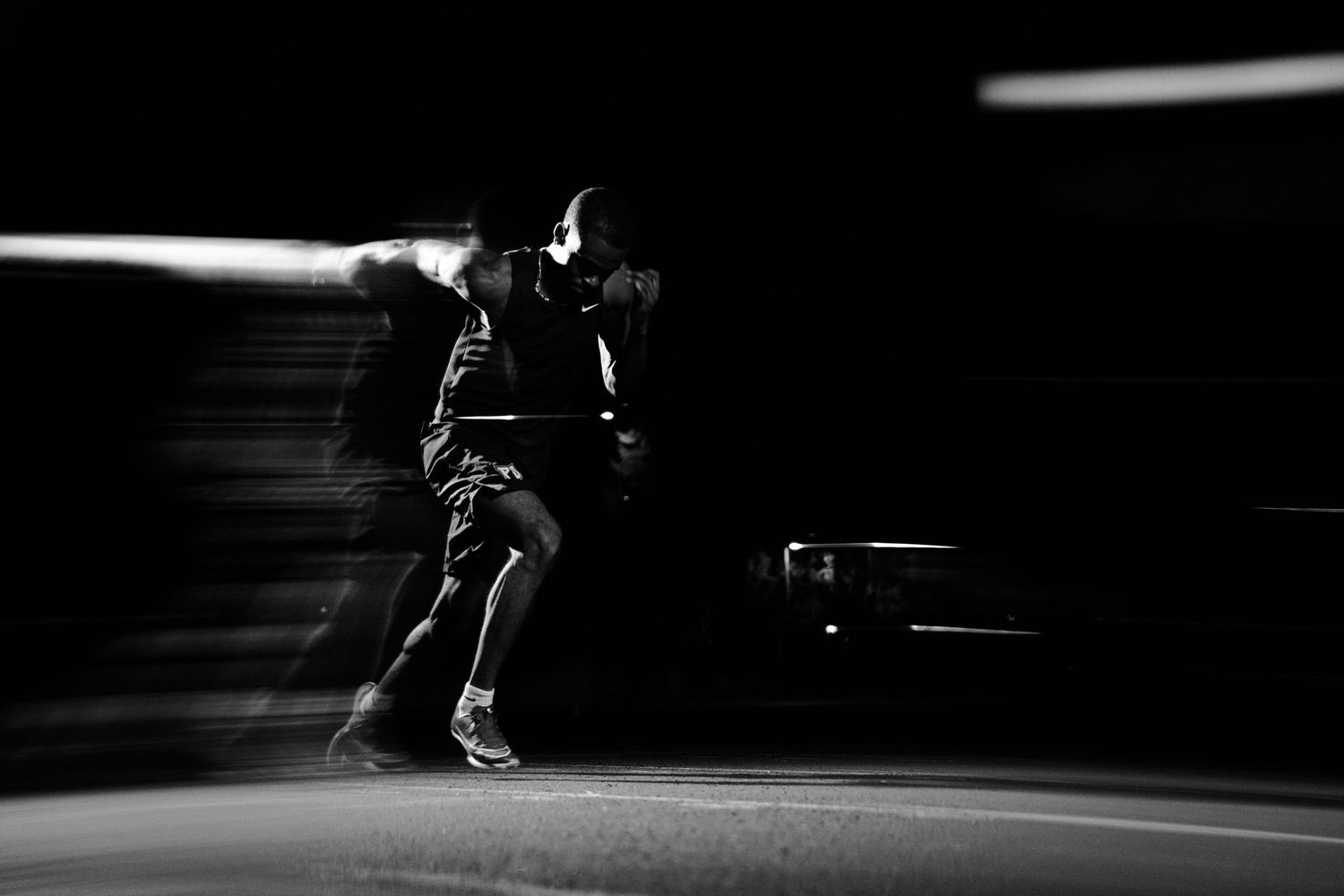 Black and white photo of a boxer in motion with dynamic blur effect in a dark arena.