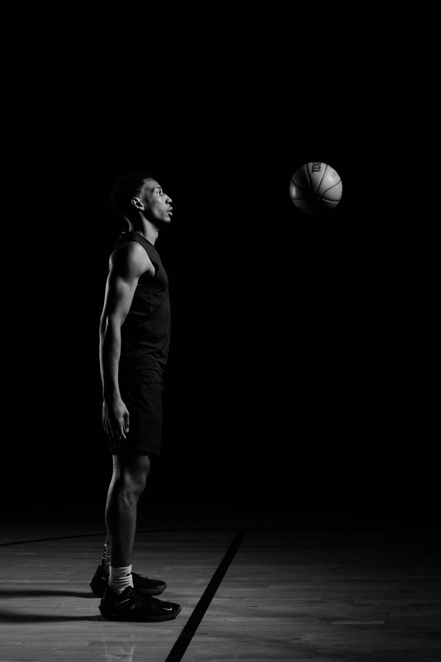 Silhouetted figure standing against dark background in artistic black and white composition.