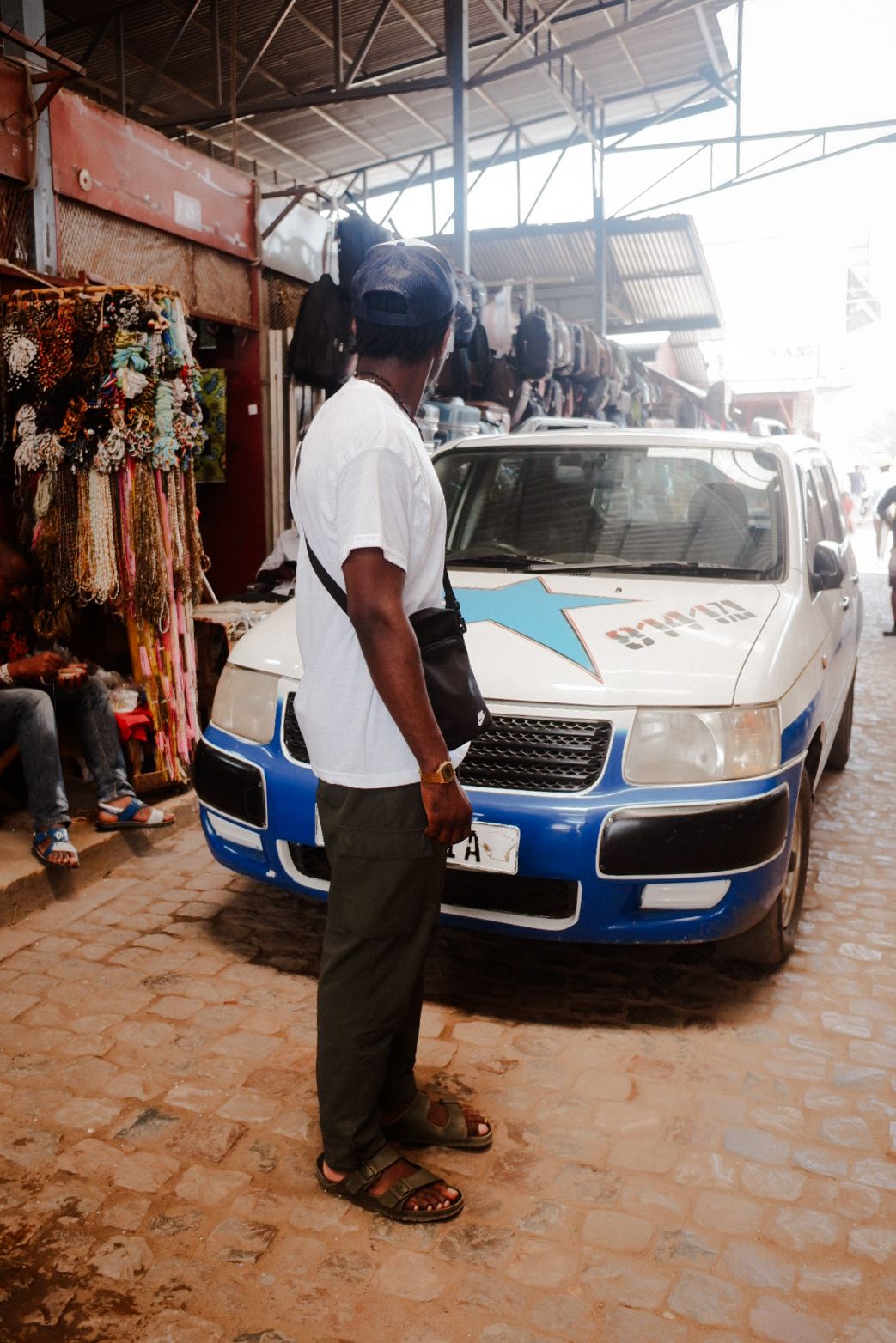Blue and white police vehicle parked inside a covered market area.