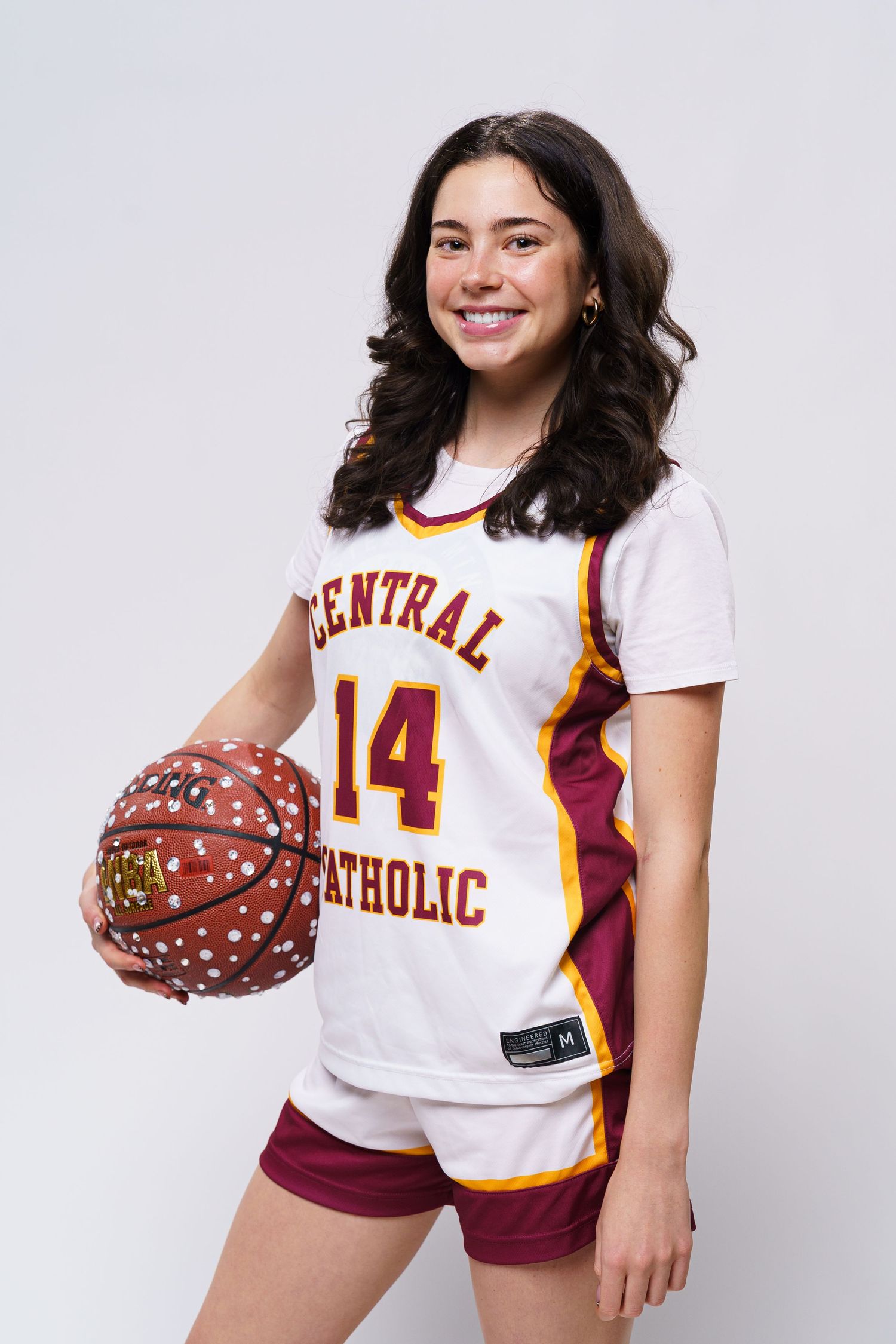 Basketball player in white Central Catholic jersey number 14 poses with decorated ball.