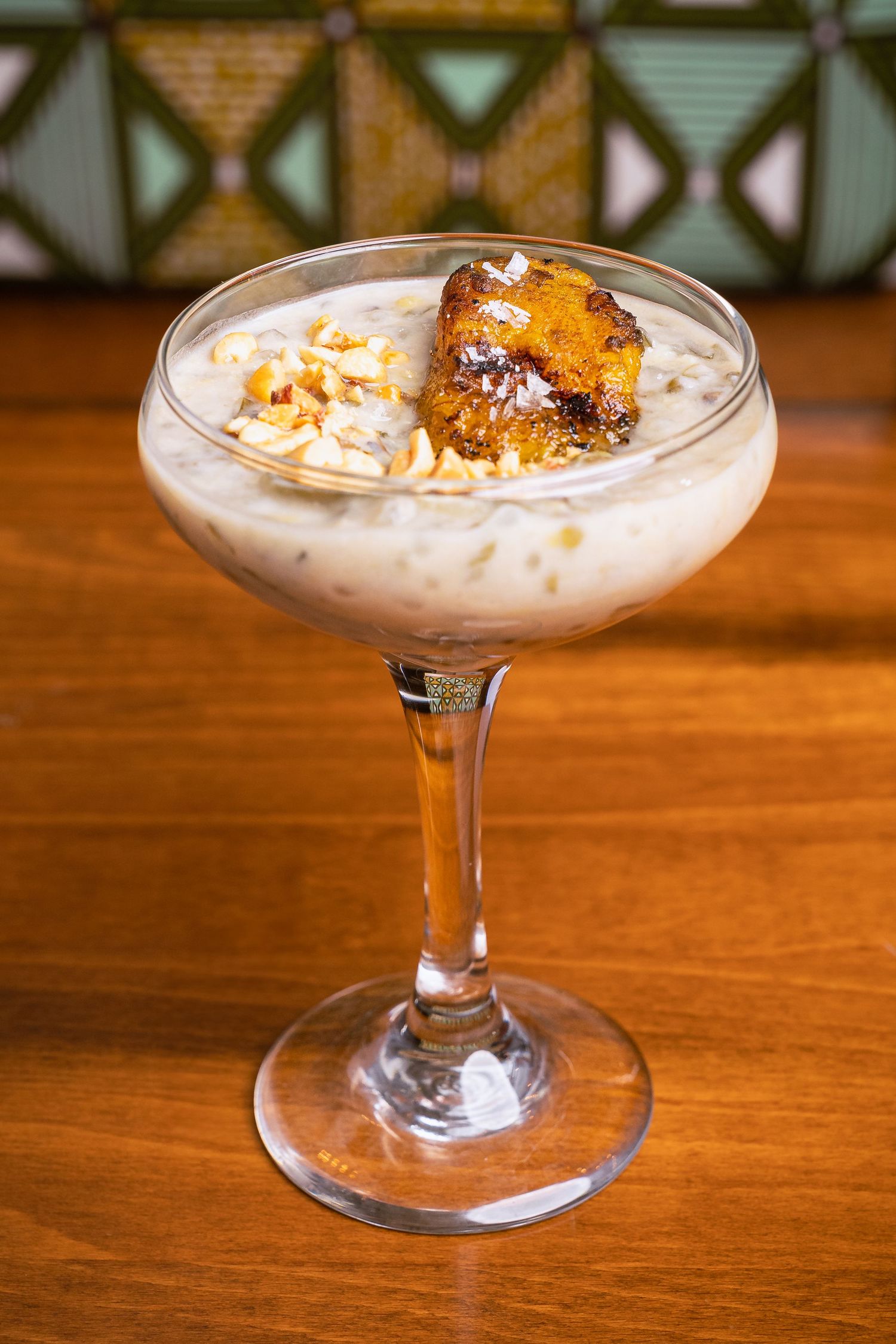 Creamy dessert in a coupe glass topped with honeycomb and crushed nuts.