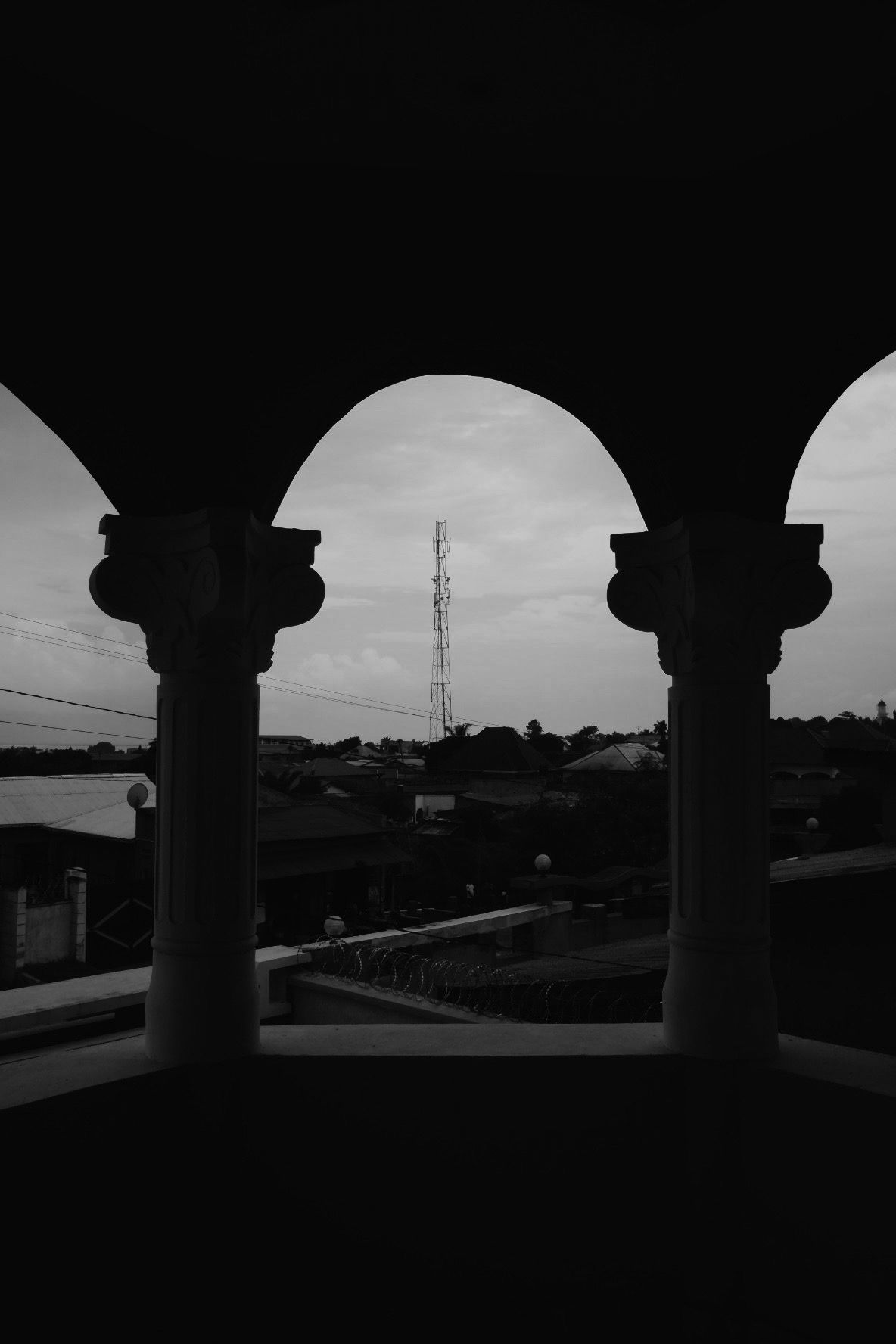 Architectural columns frame a silhouetted cityscape view at dusk.