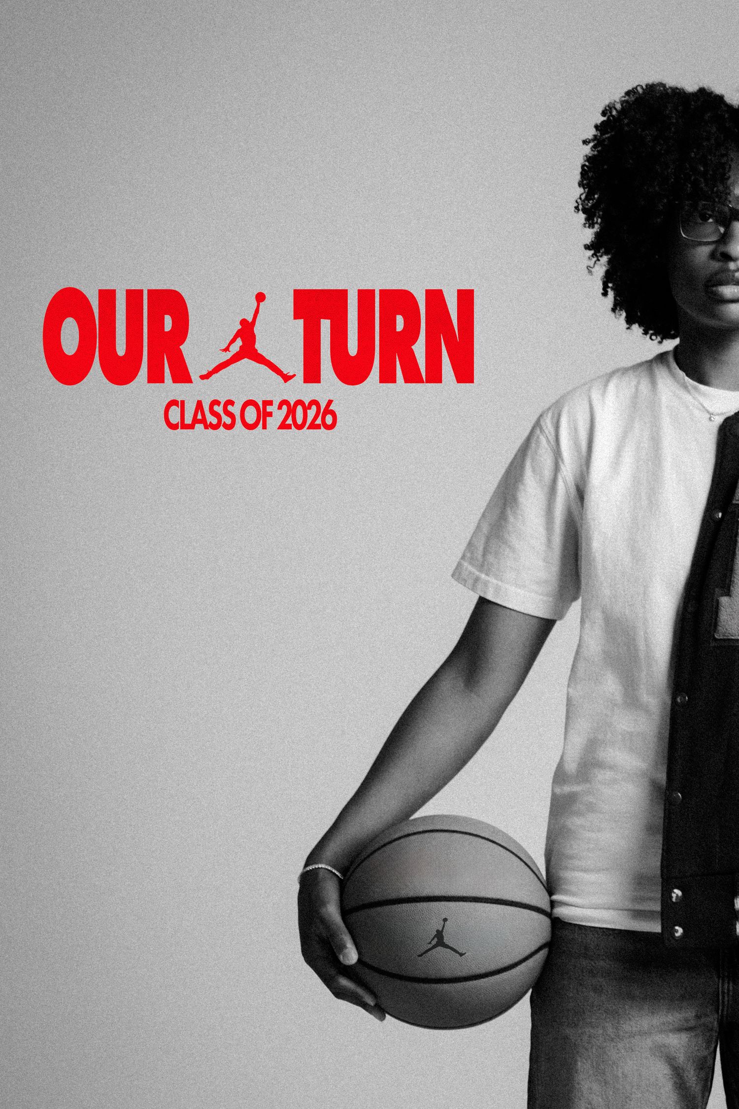 Black and white photo of a young man holding a basketball beside the Jordan Brand Our Turn Class of 2026 logo.