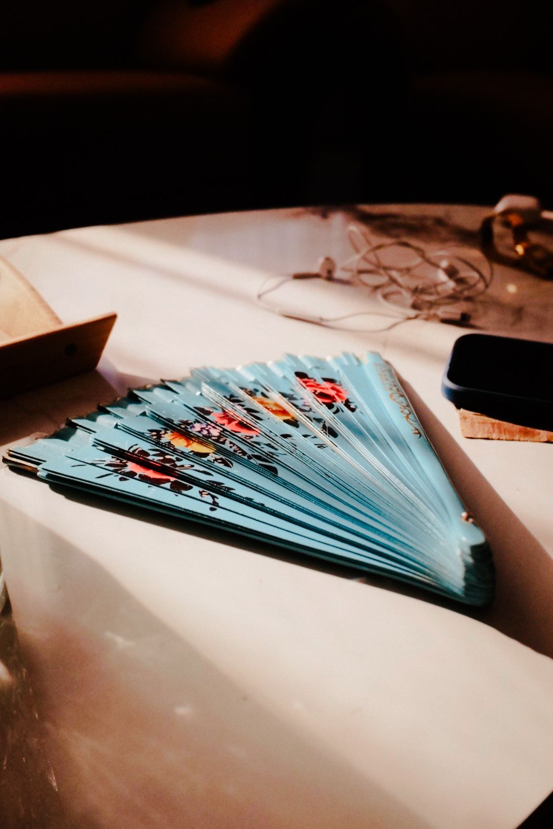 Stack of blue papers or documents fanned out on a white surface in dramatic lighting.