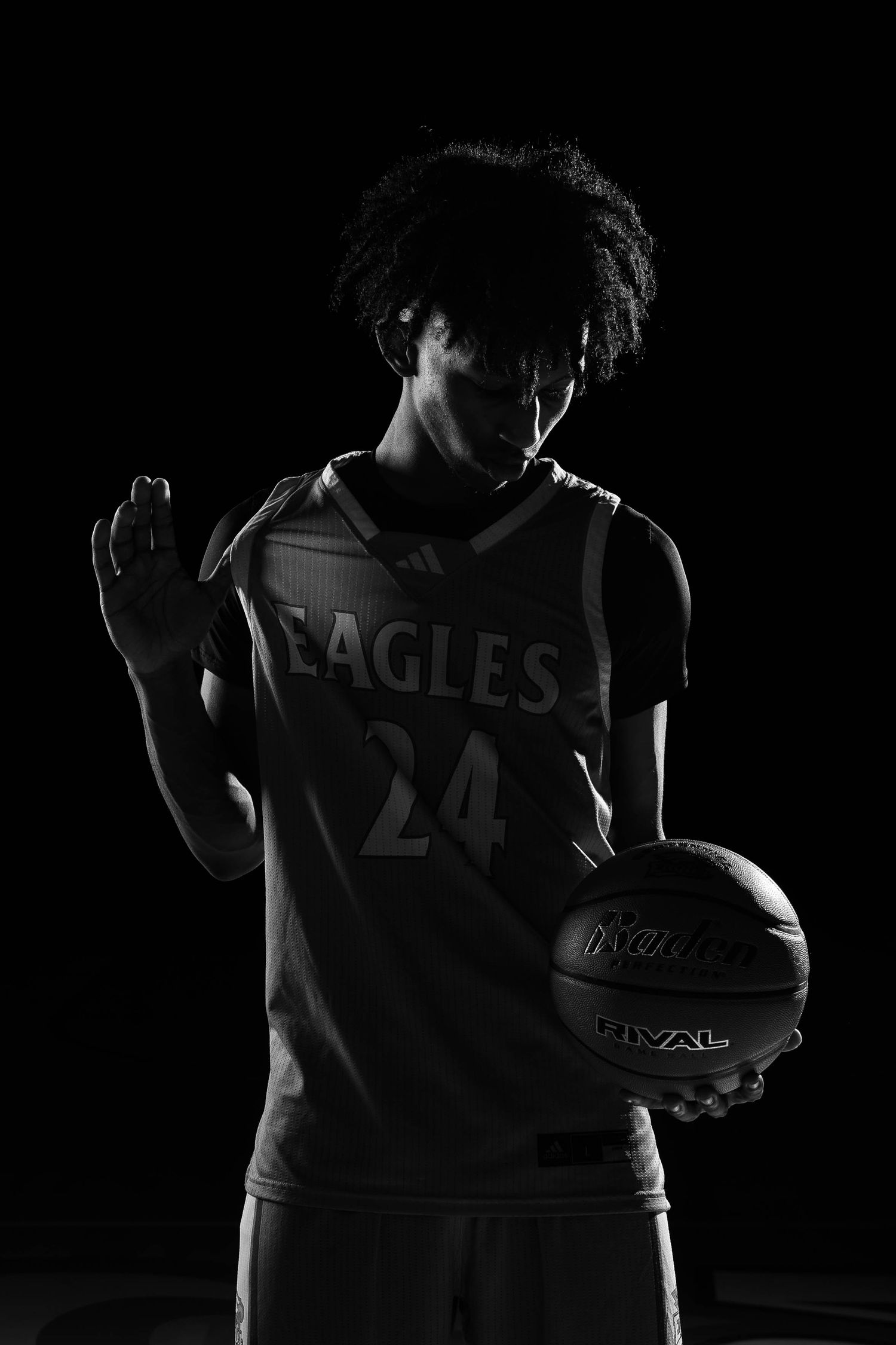 Low-key dramatic lighting on basketball jersey number 24 against dark background.