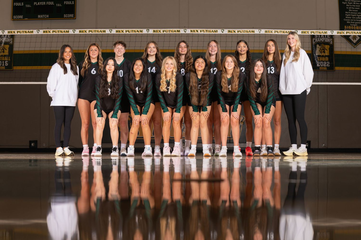 Volleyball team lined up for official team photo in white uniforms.