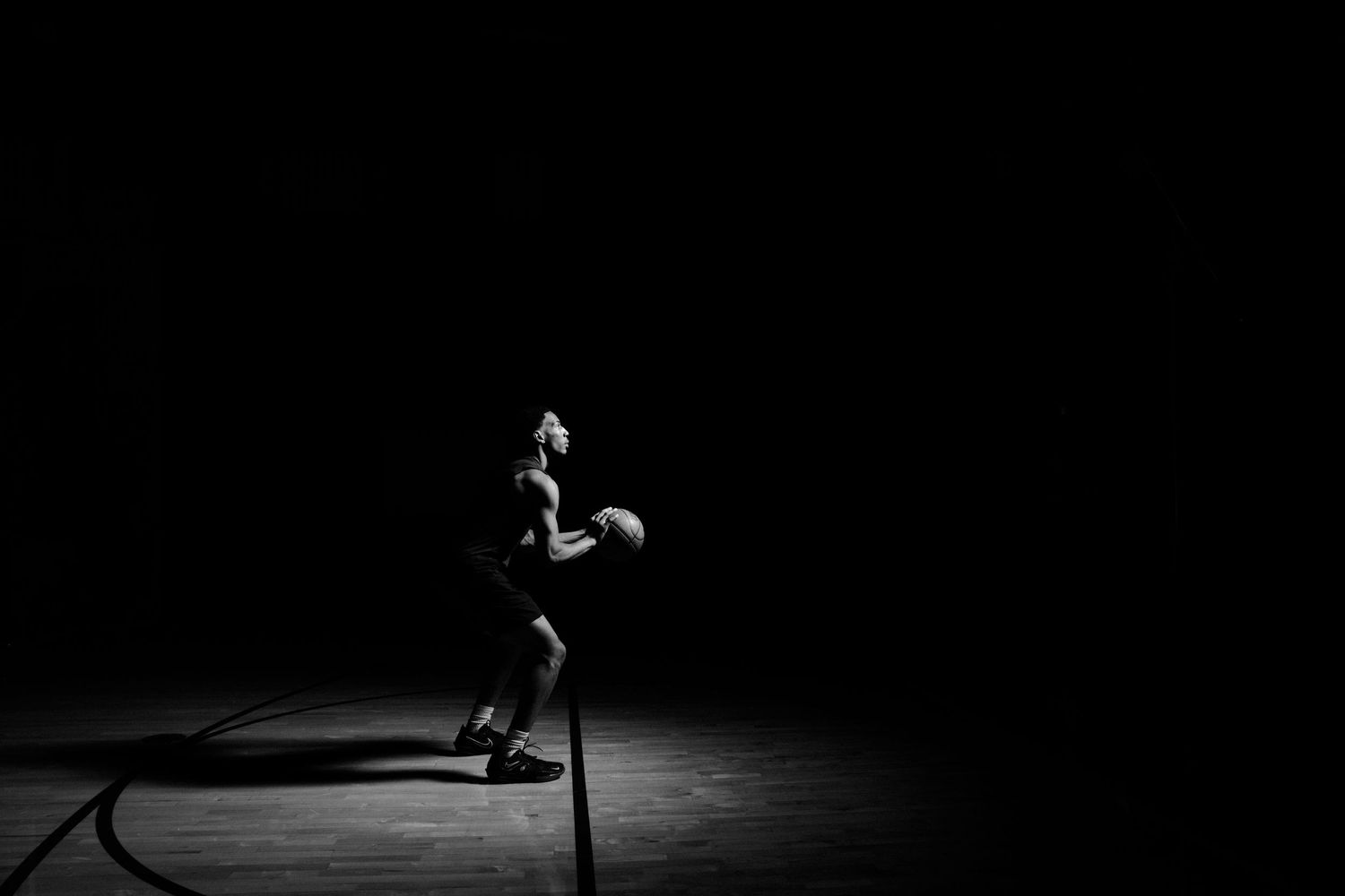 Dramatic black and white portrait series of an athlete in a dark studio setting.