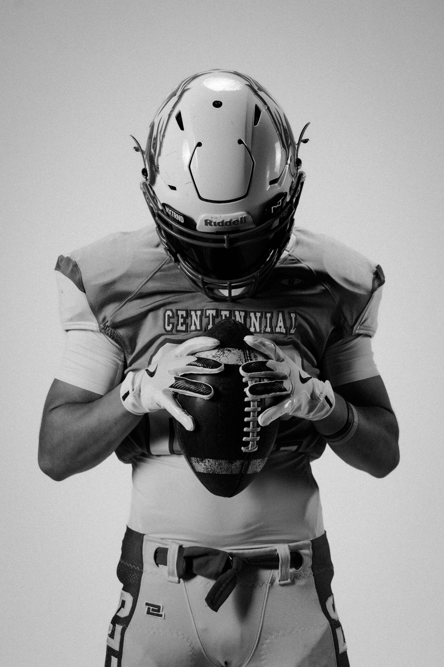 Football player demonstrates ball handling techniques in monochrome studio setting.