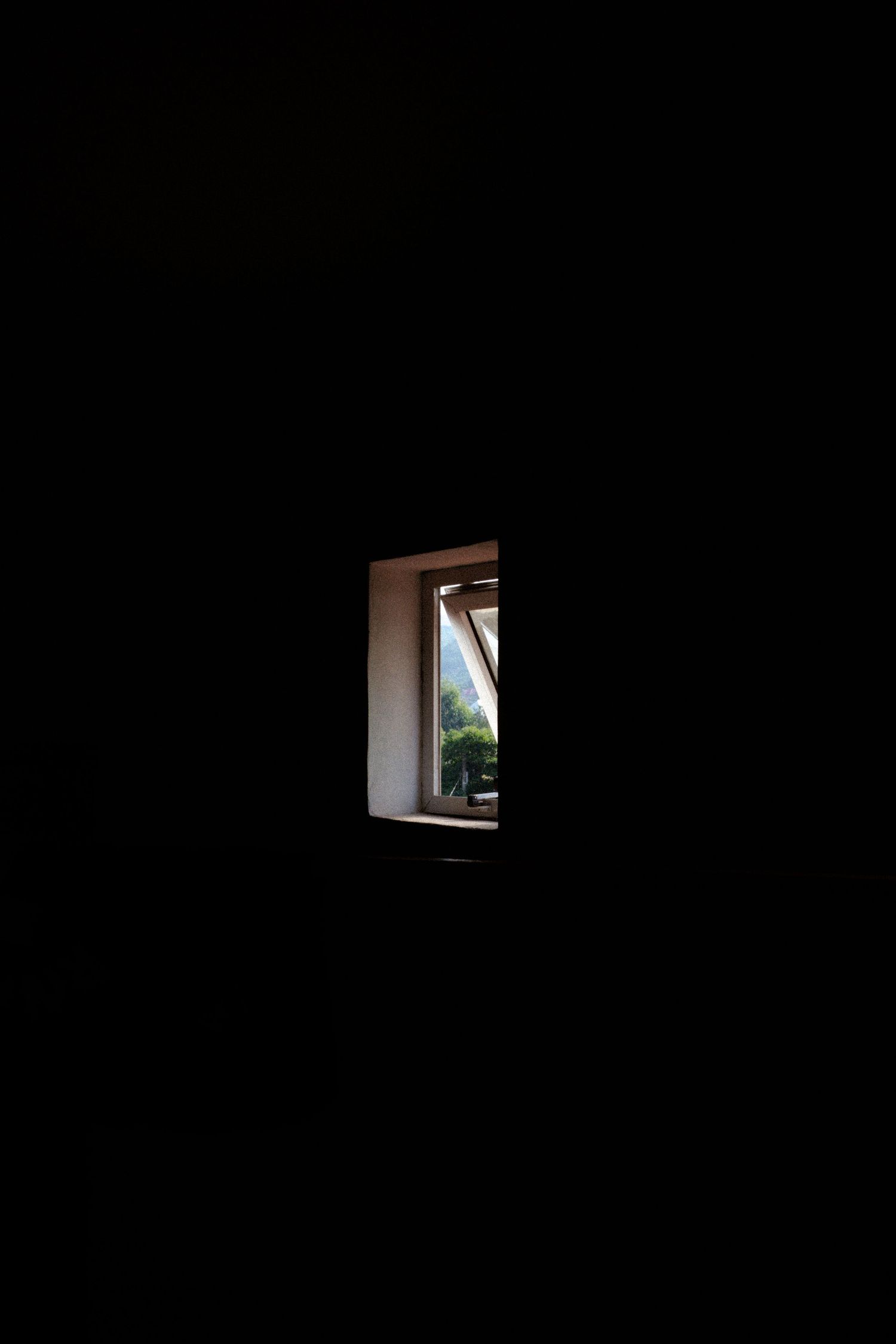 A dark window frame silhouetted against a black background creates a minimalist architectural composition.