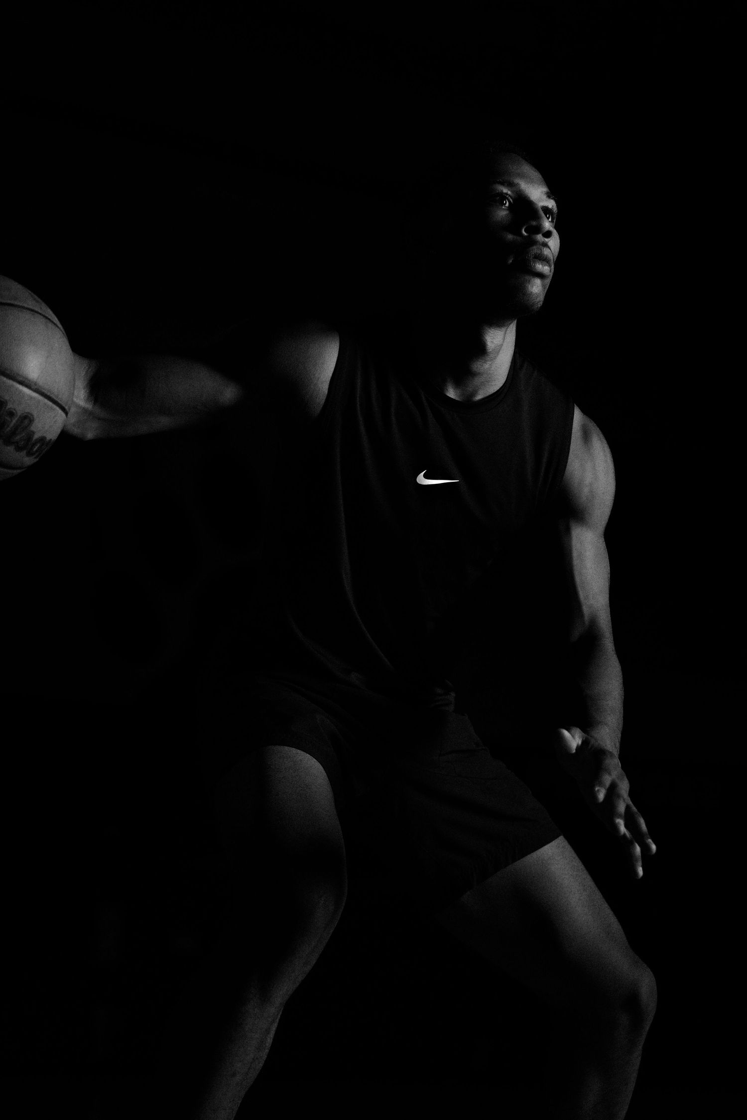Athletic figure in Nike basketball gear photographed in contrasting shadows.
