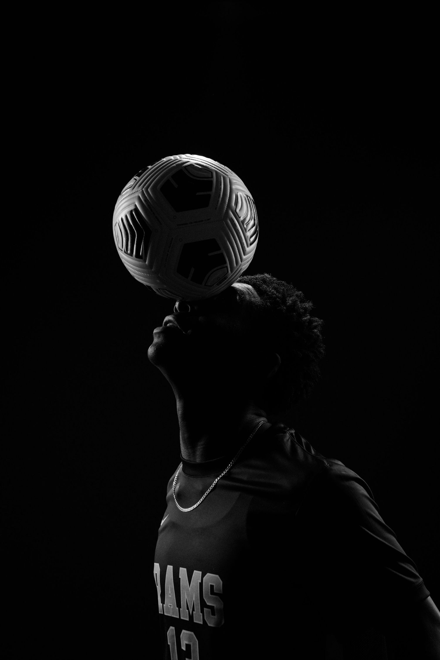 Dramatic low-key portrait series of athlete in dark uniform against black background.