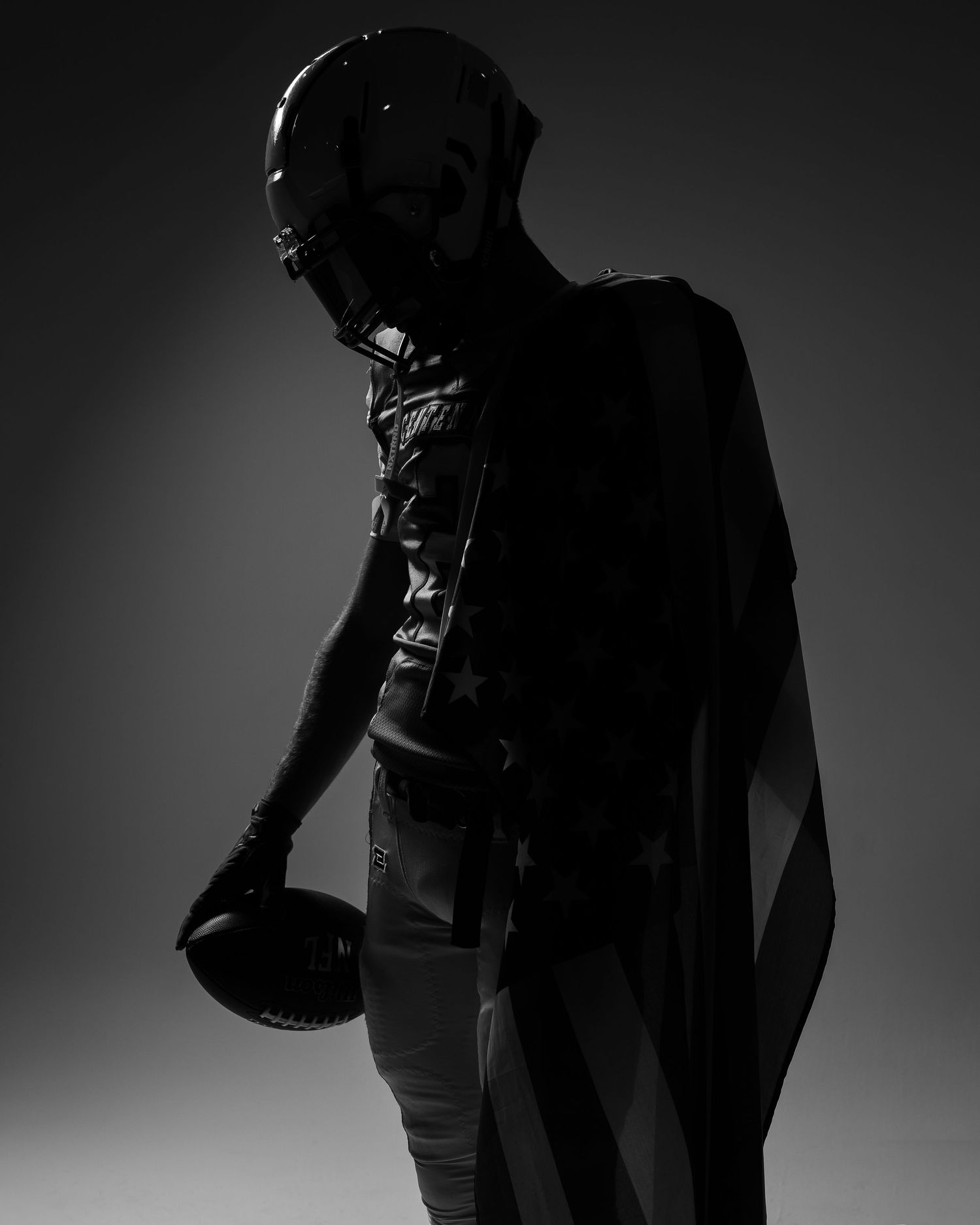Silhouetted football players with equipment in dramatic studio lighting.