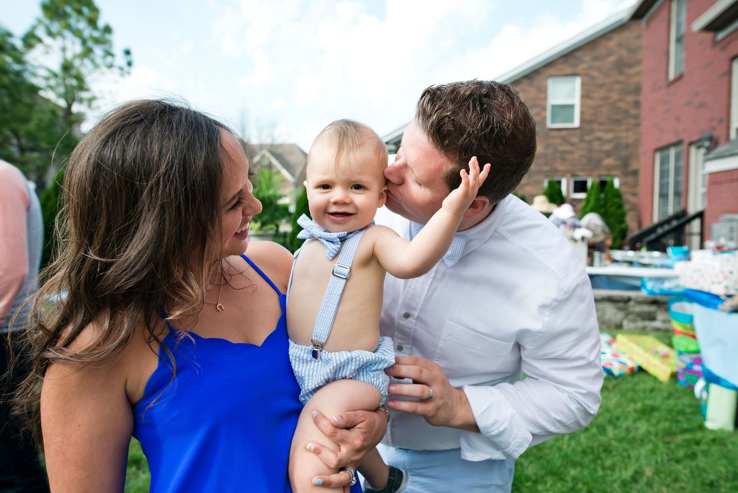 A family shares a joyful moment together in their backyard with outdoor toys visible in the background.