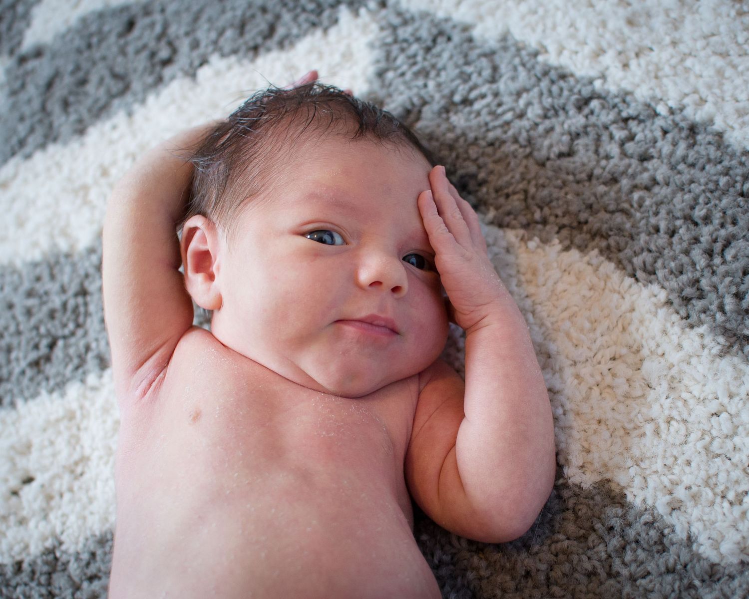 Newborn baby resting on soft gray blanket shown from different angles in a series of connected photos.