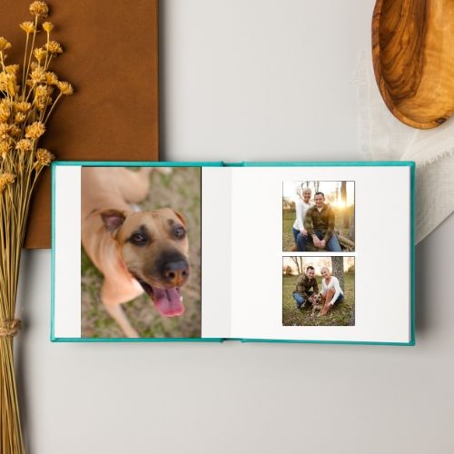 A rustic wooden photo album display with dried flowers and natural decor elements arranged on a brown surface.
