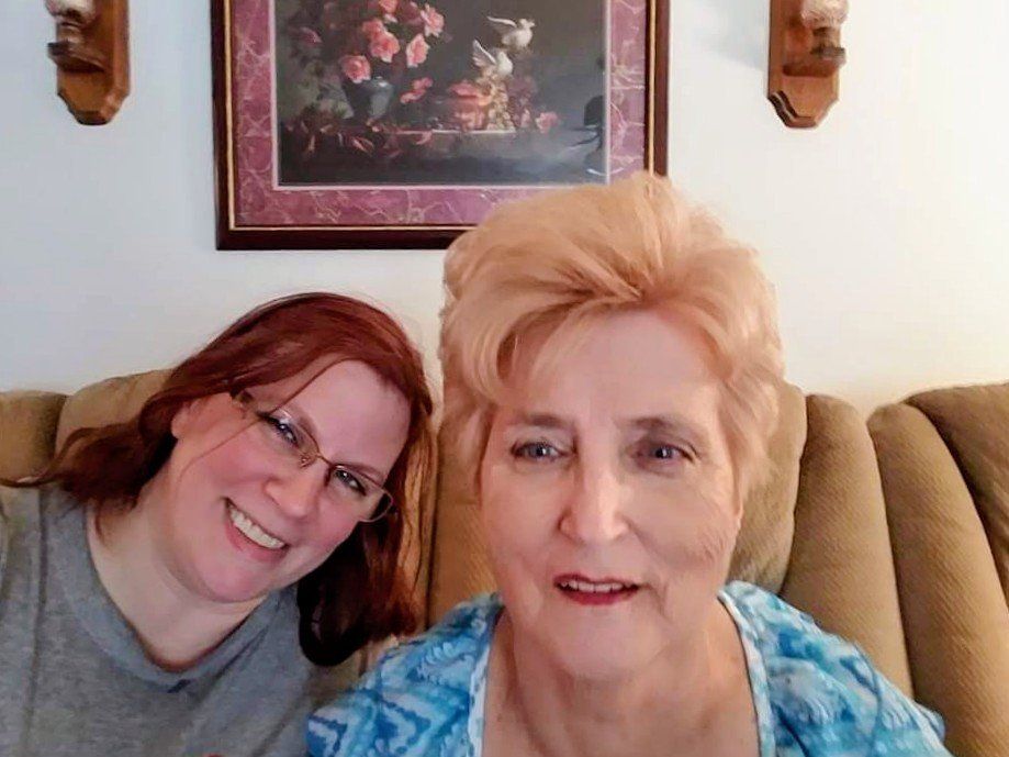 Two people sitting together on a beige couch in a living room setting.