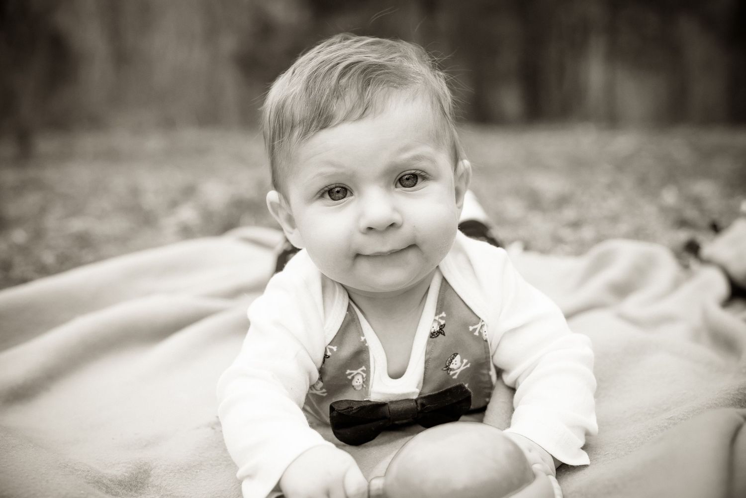 A series of black and white portraits showing a baby in different expressions and poses.