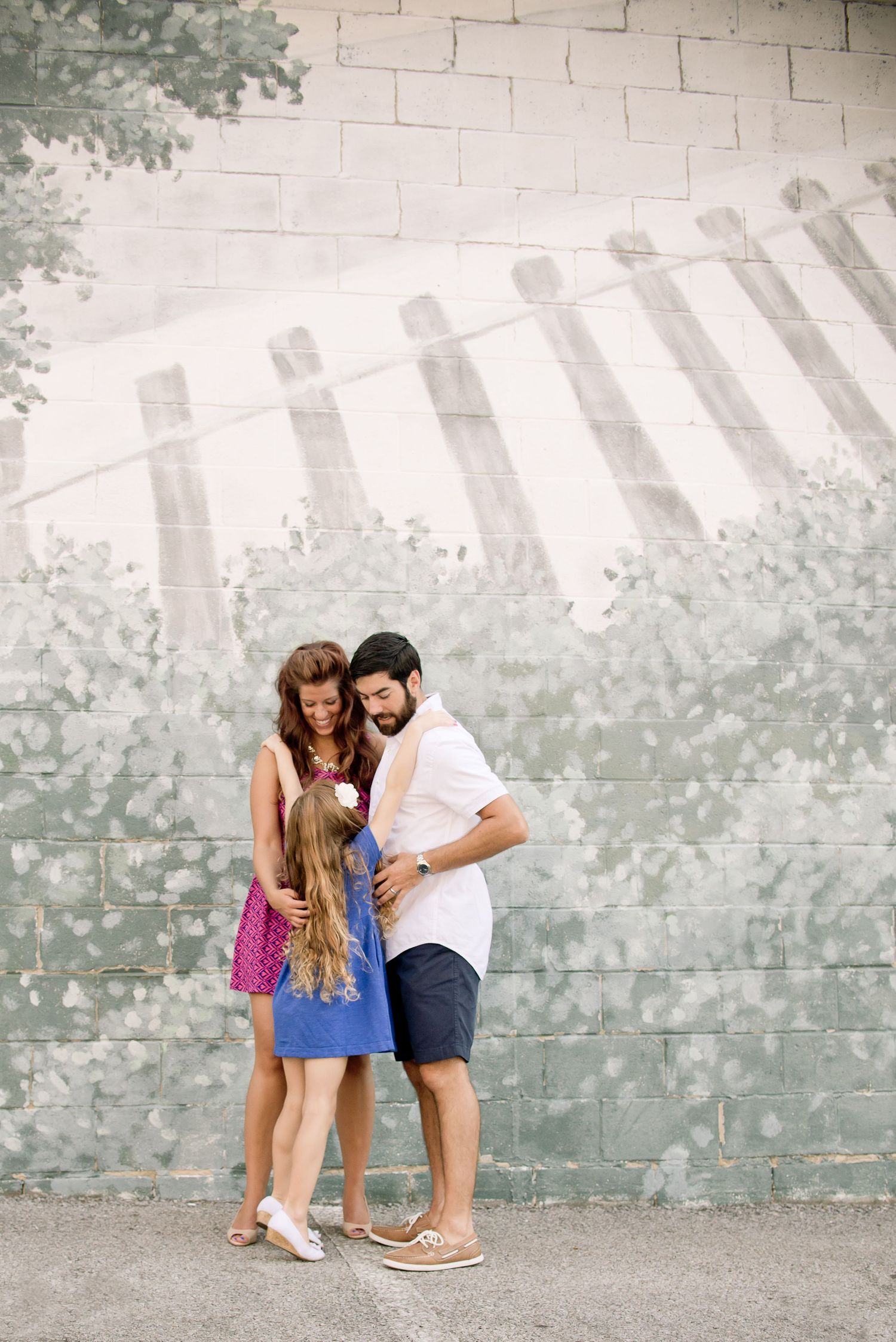 A couple shares a tender moment against a concrete wall in a series of candid romantic poses.
