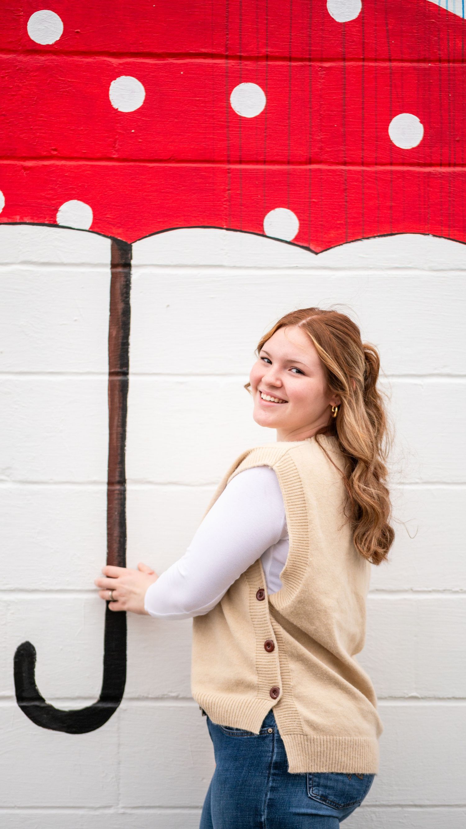 A creative portrait against a red and white polka dot umbrella mural.