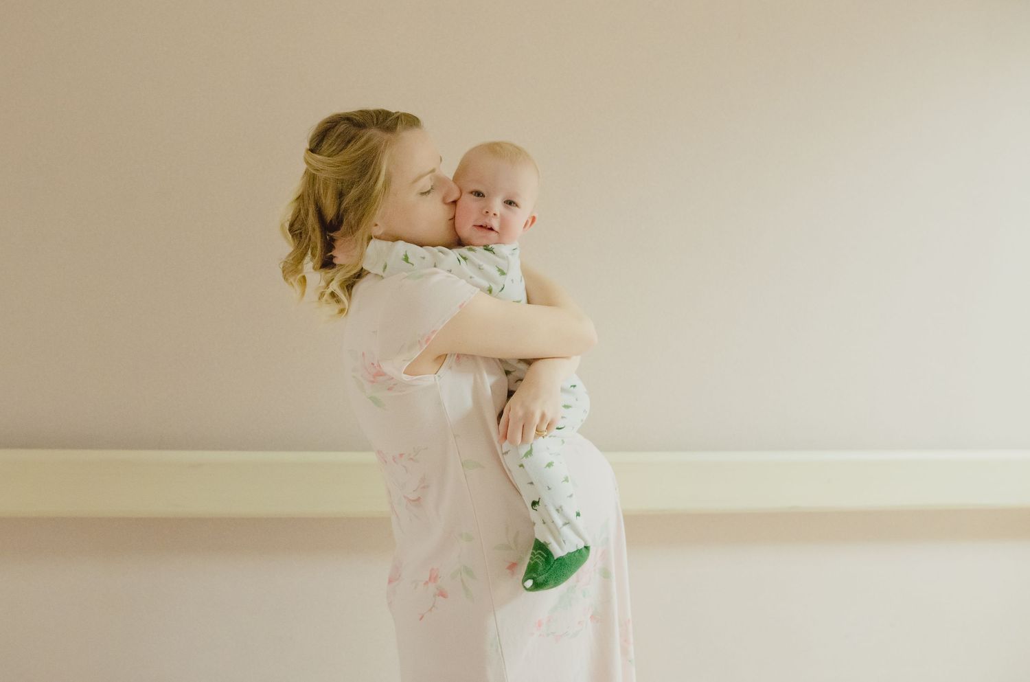 Tender embrace captured in soft, natural light against a neutral wall background.