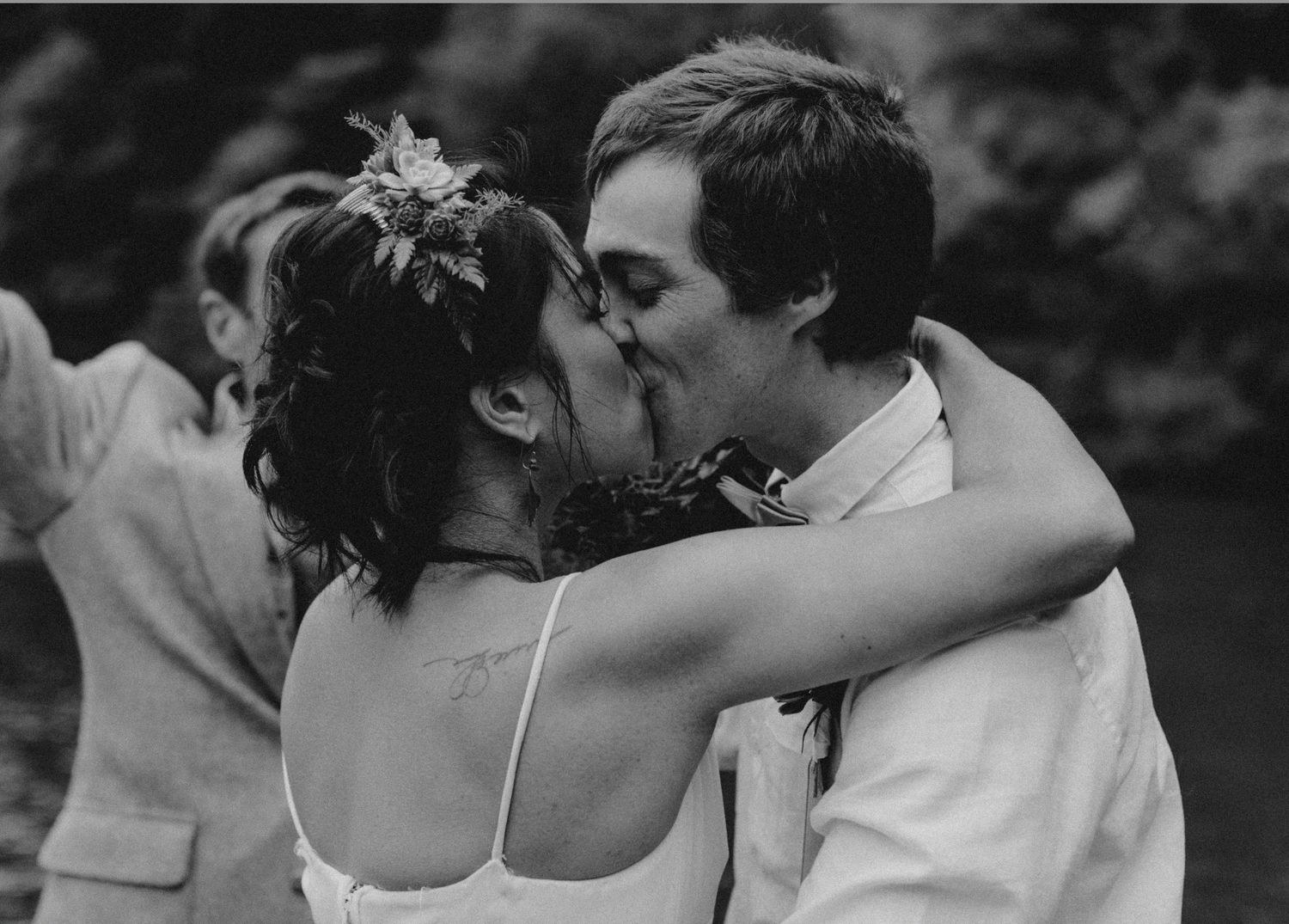 Black and white photo of bride and groom sharing a first kiss at their wedding ceremony.