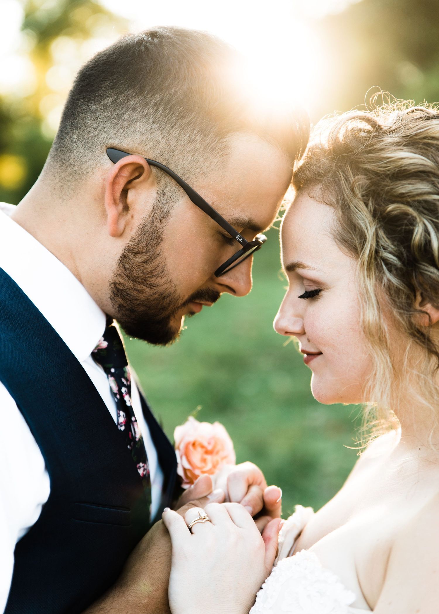 Bride and groom touching foreheads tenderly in golden sunset light.